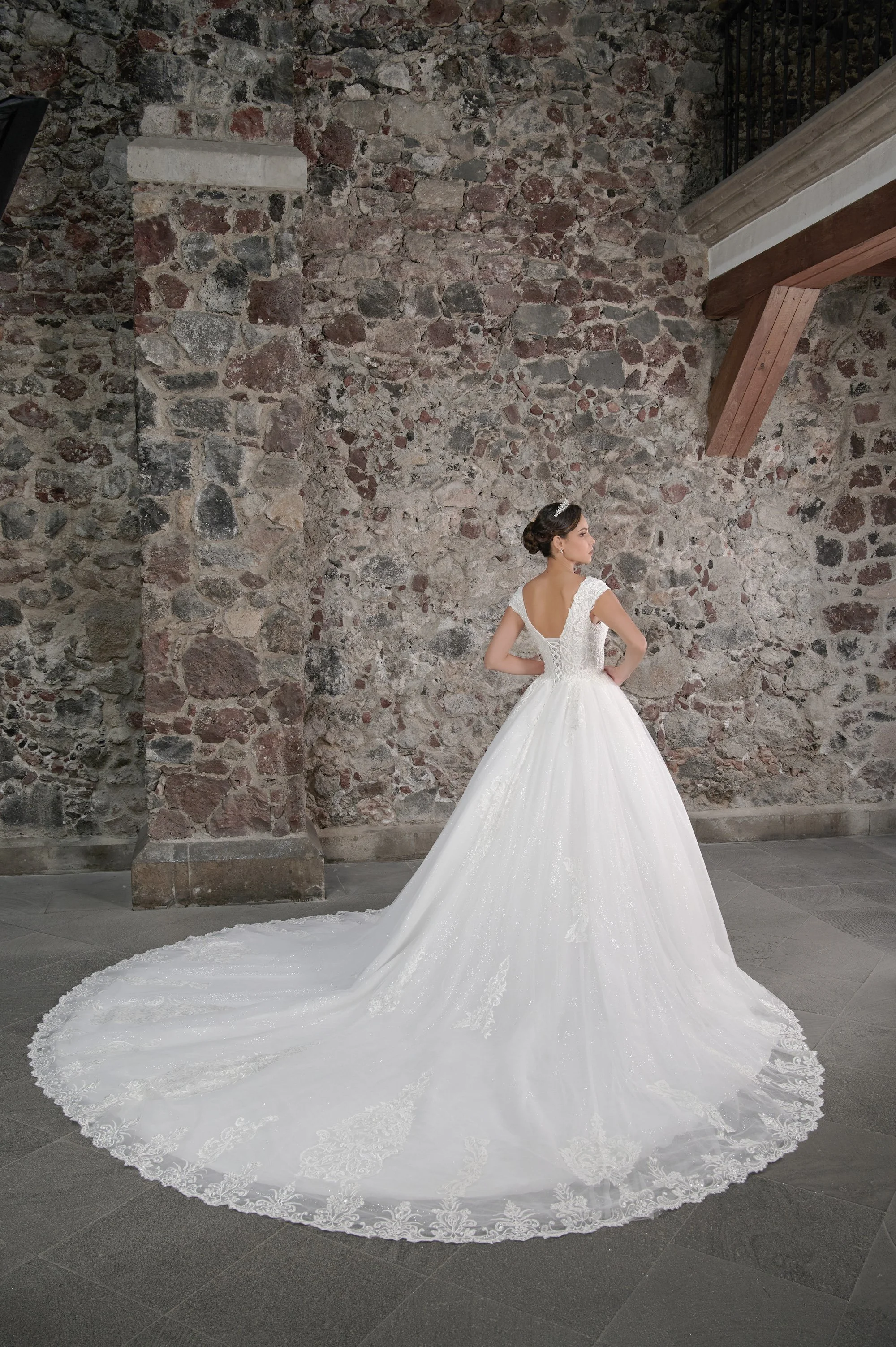 Espalda del vestido de novia Cune con corsé de cintas cruzadas y cola larga.