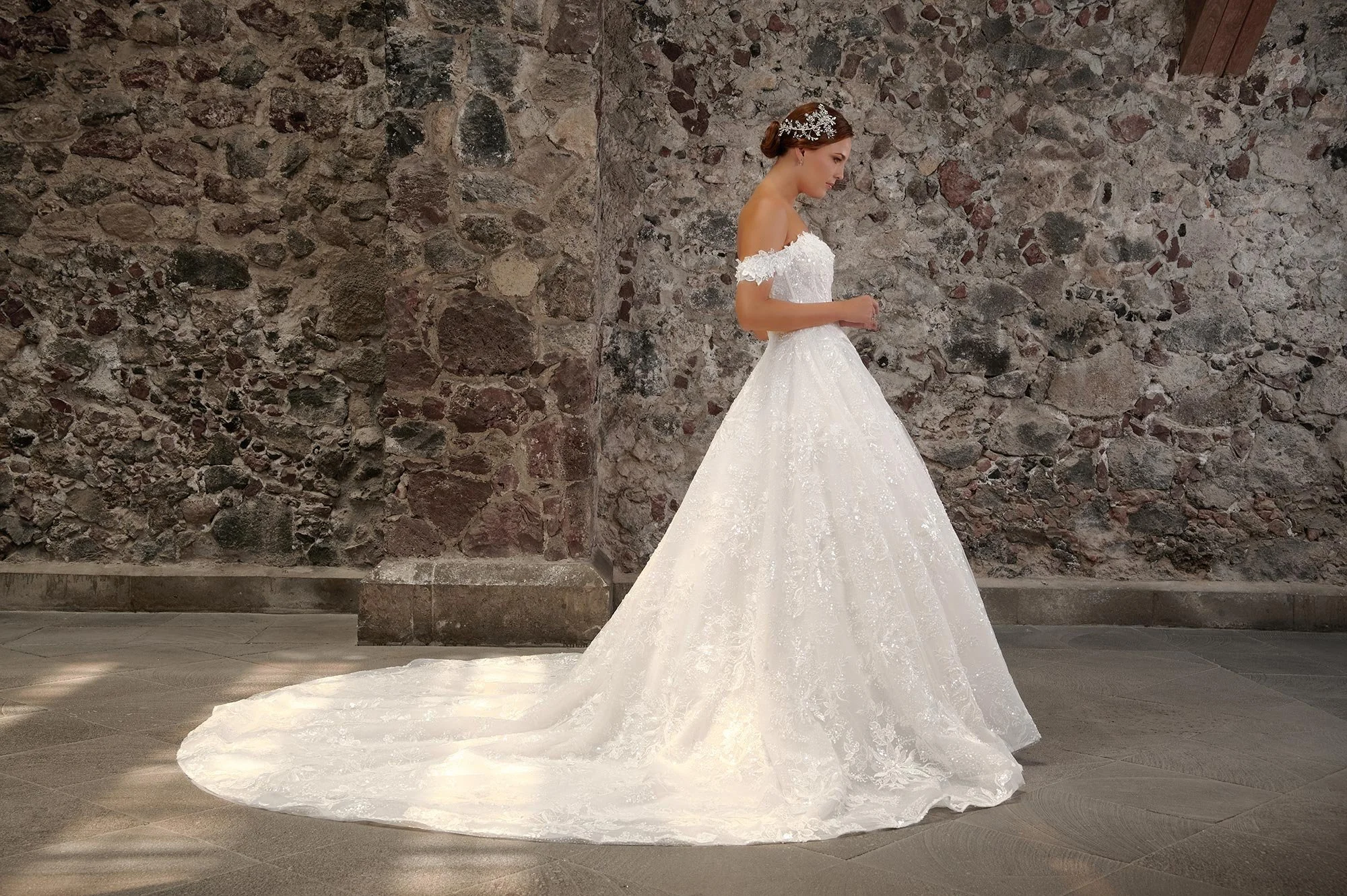 Vista lateral del vestido de novia Carmelia mostrando el volumen de la falda de tul y la cola larga.