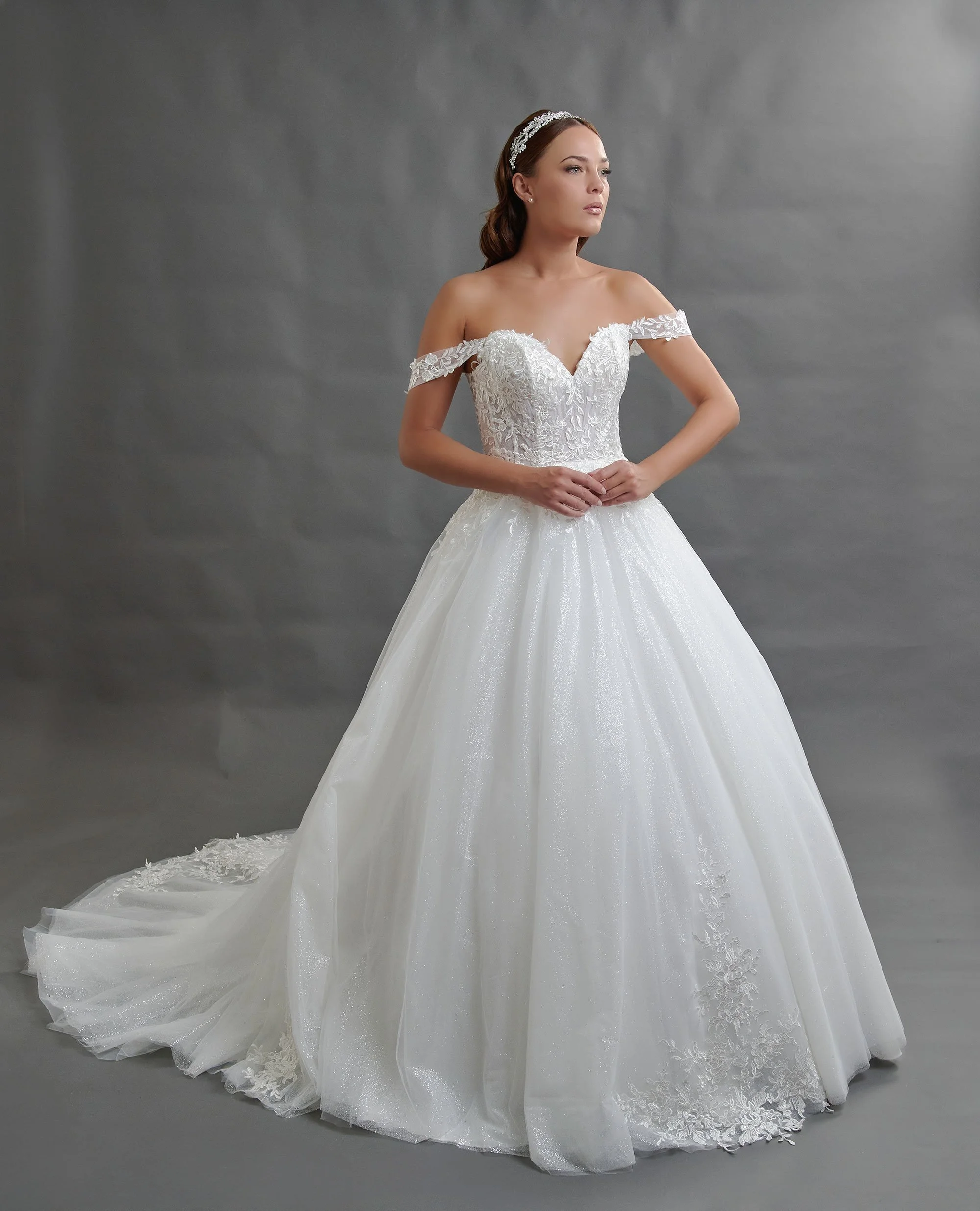 Novia con el vestido Baeza de Bridenformal, princesa de tul con brillo, escote corazón y mangas caídas de encaje, vista frontal con cola.