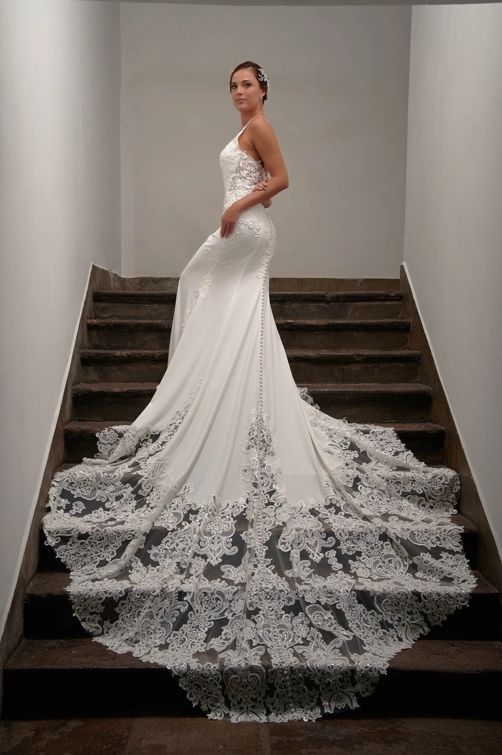 Vista lateral del vestido de novia Beterra mostrando la silueta sirena y la larga cola de encaje.