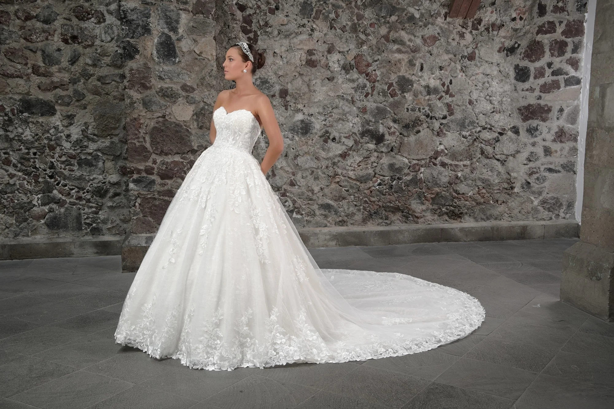 Novia con el vestido Calvin de Bridenformal, princesa strapless de tul con encaje floral y escote corazón, vista frontal con cola.