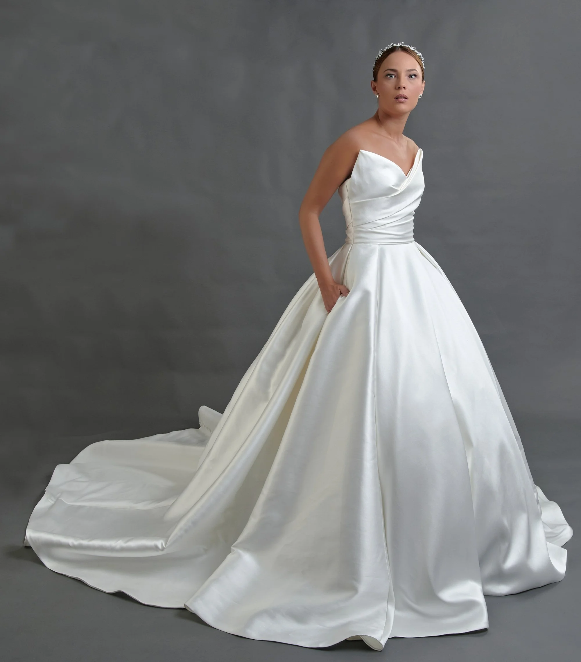Novia con el vestido Bella de Bridenformal, princesa de satén minimalista con pliegue escultórico, vista frontal con cola.