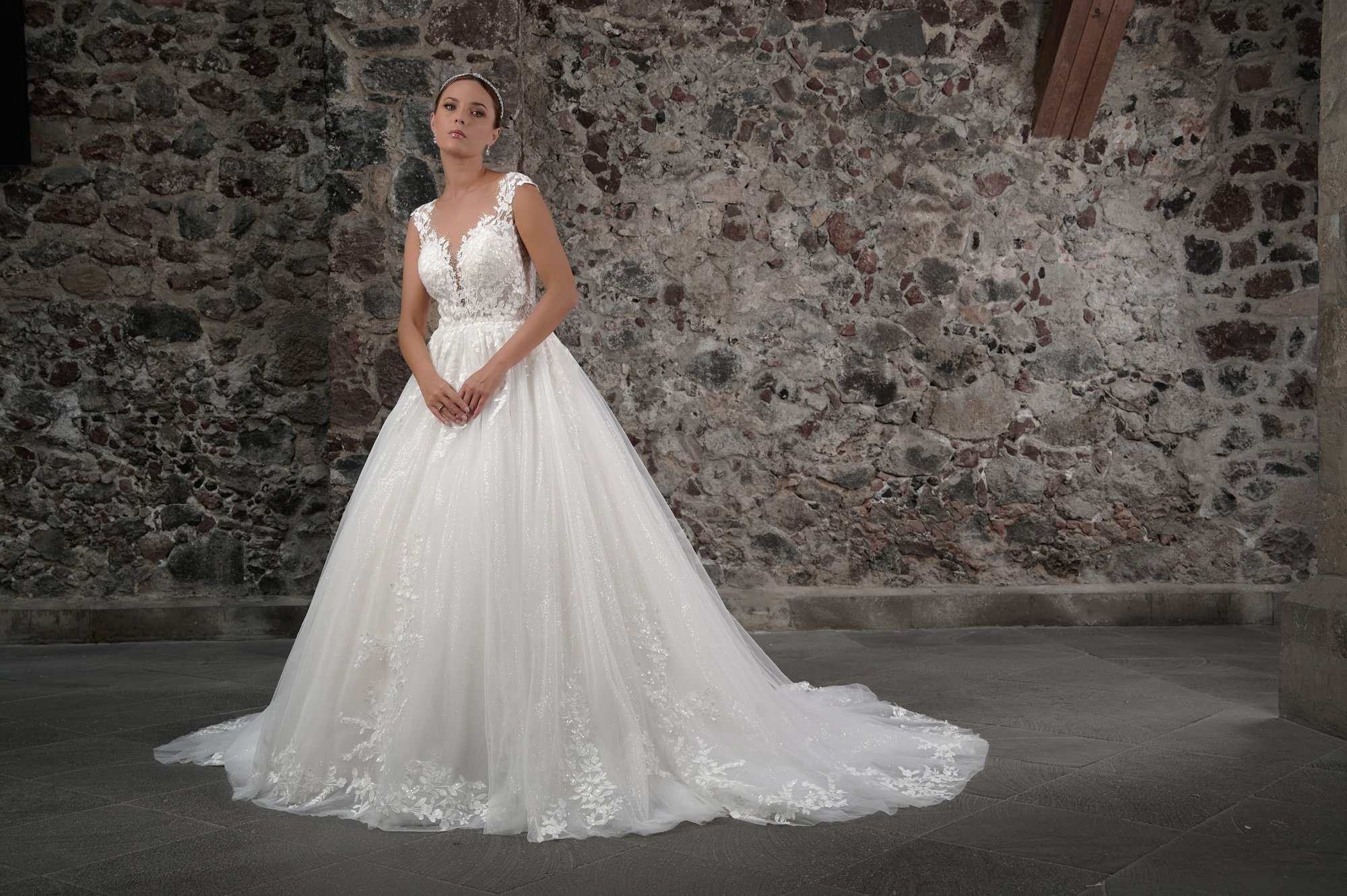 Novia con el vestido Coral de Bridenformal, princesa de tul con encaje floral y escote en V, vista frontal con cola.