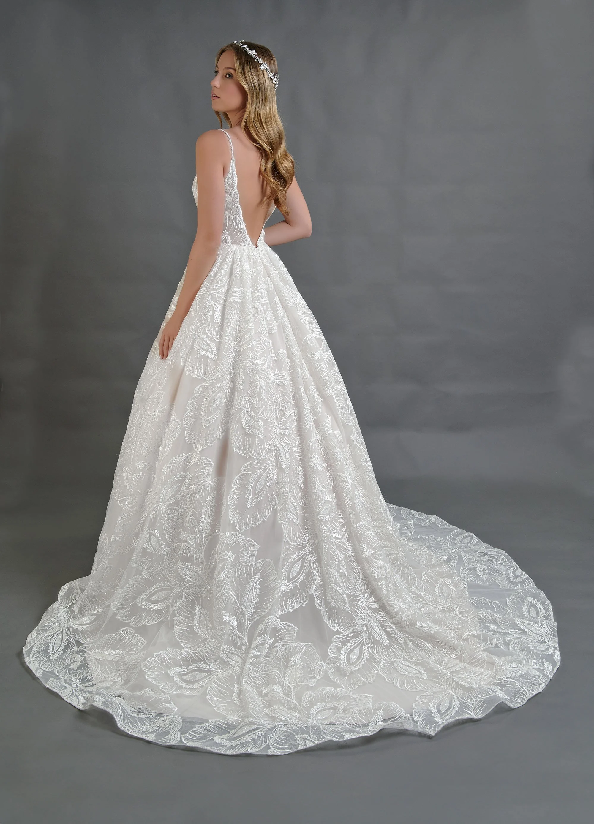 Espalda del vestido de novia Berlin con escote profundo en V y falda bordada con cola larga.