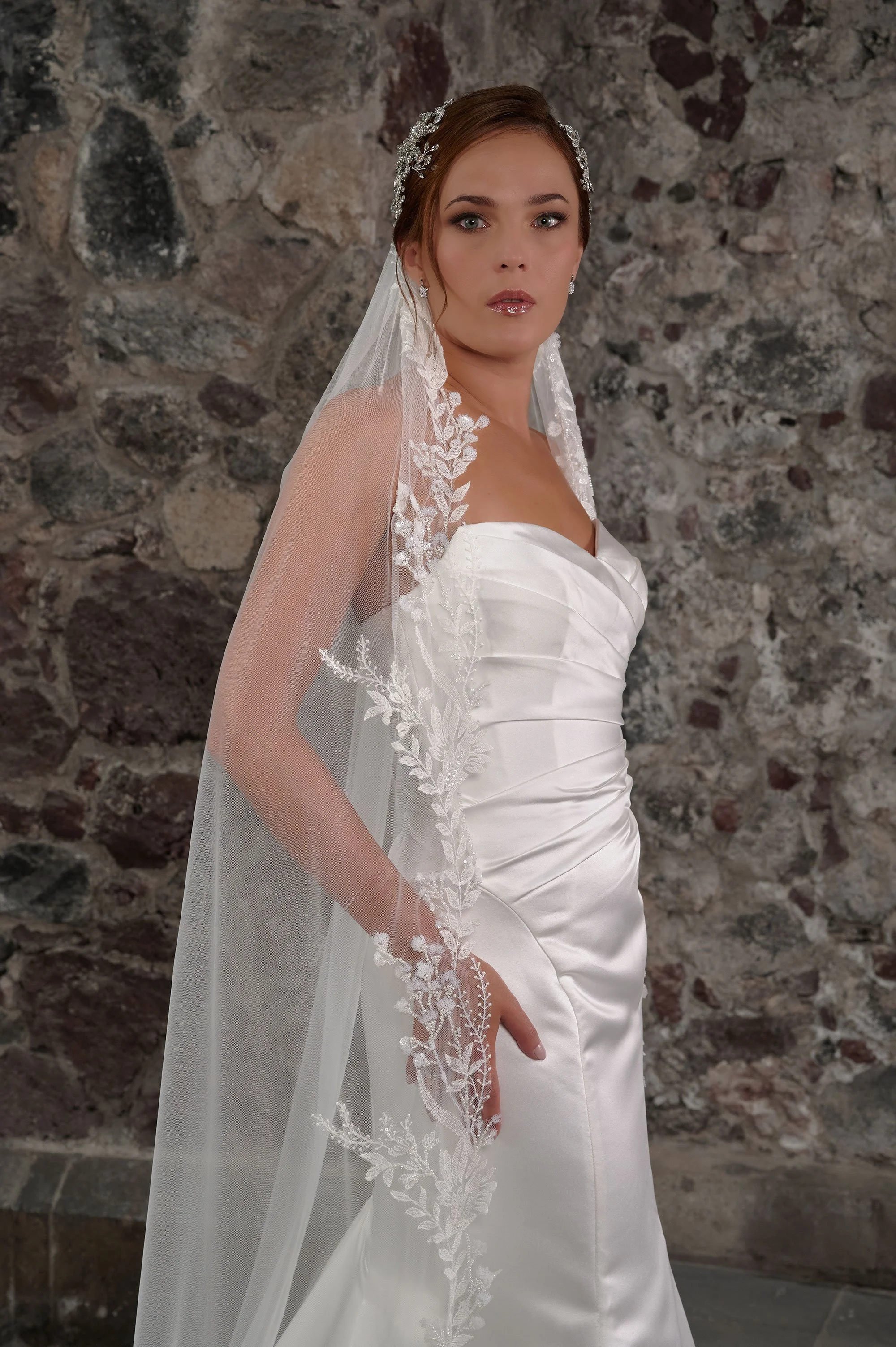 Detalle del escote corazón y el drapeado de satén del corpiño del vestido de novia Cibeles, con velo de encaje.