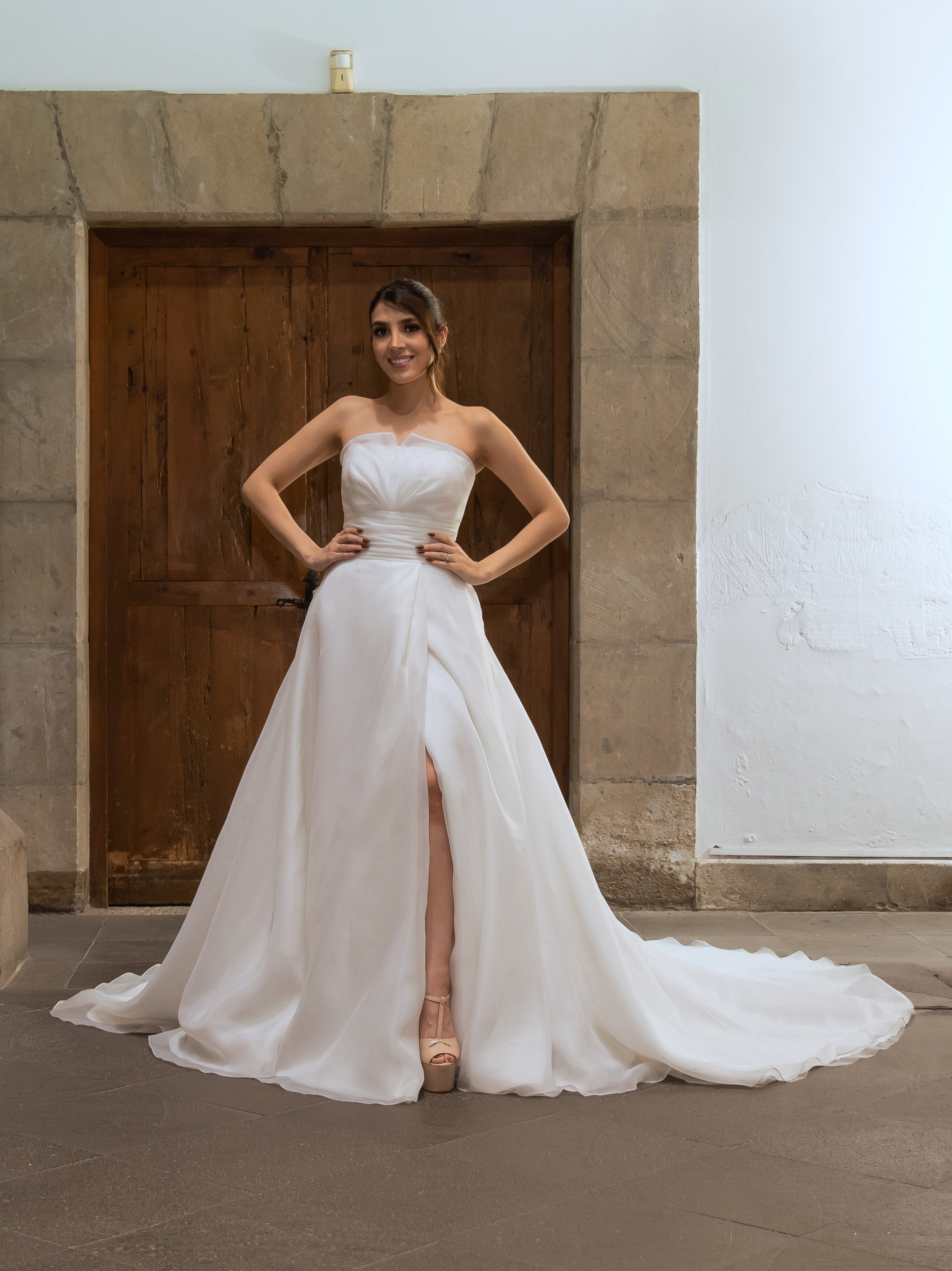 Novia con el vestido Wichita de Bridenformal, línea A de organza drapeada con abertura frontal, vista frontal completa.