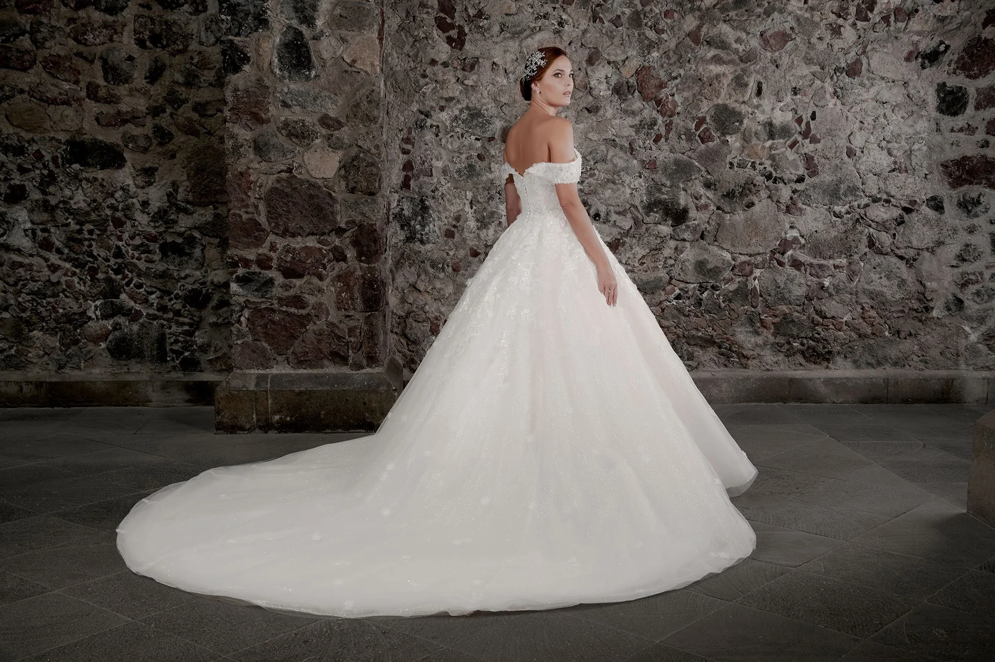 Espalda del vestido de novia Carmina con falda de tul brillante y cola larga.