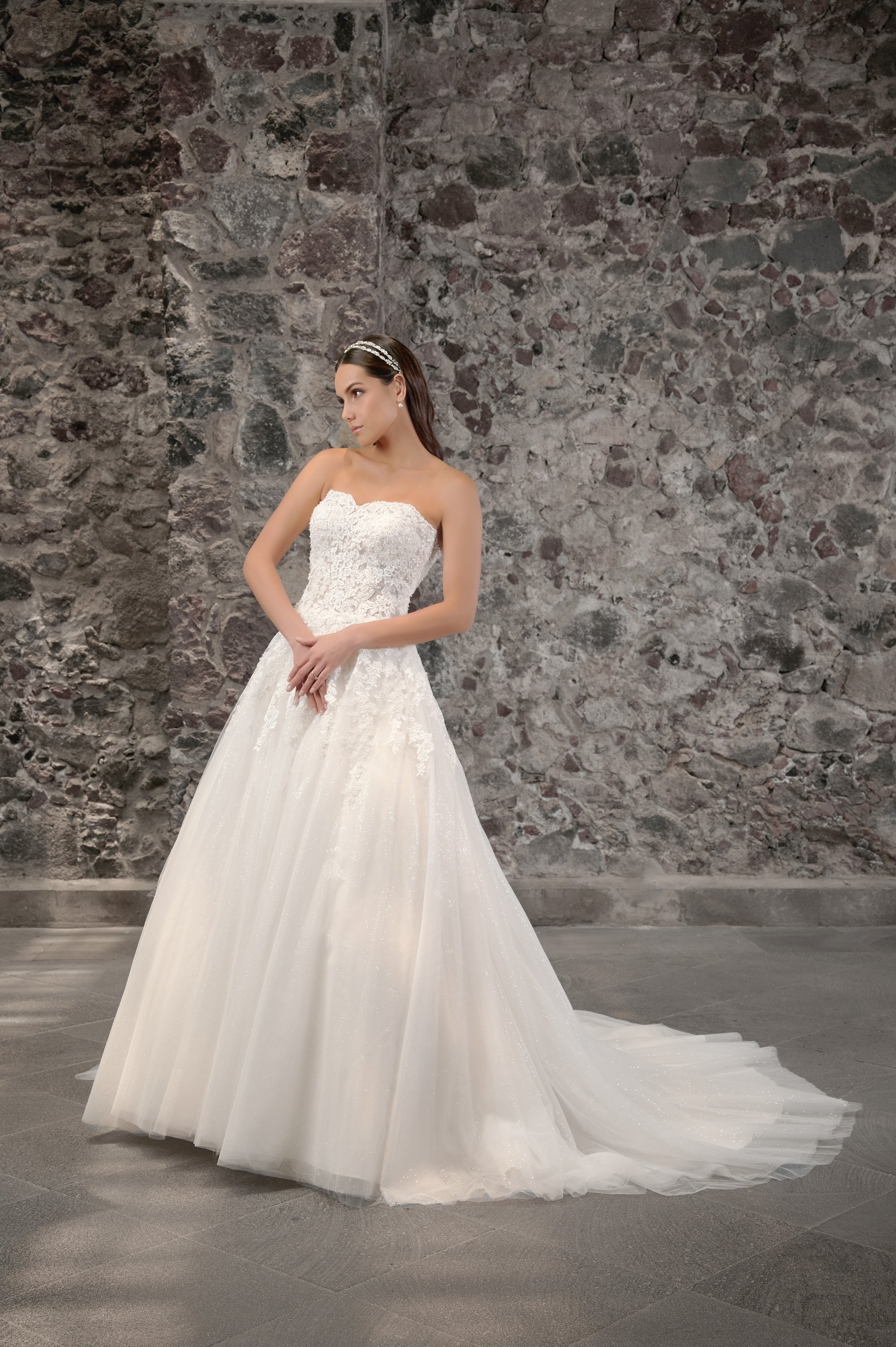 Novia con el vestido Concordia de Bridenformal, princesa strapless de encaje bordado, vista frontal con cola.