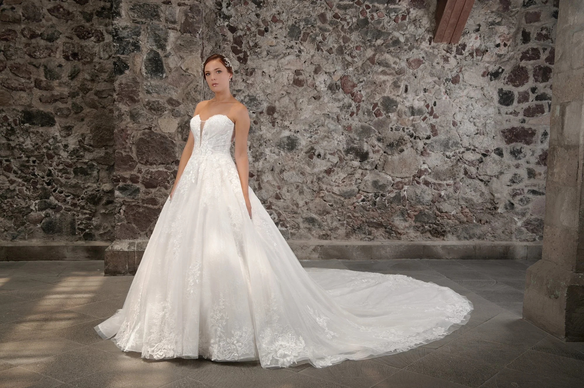 Novia con el vestido Calista de Bridenformal, princesa strapless de tul con encaje y escote corazón, vista frontal con cola.
