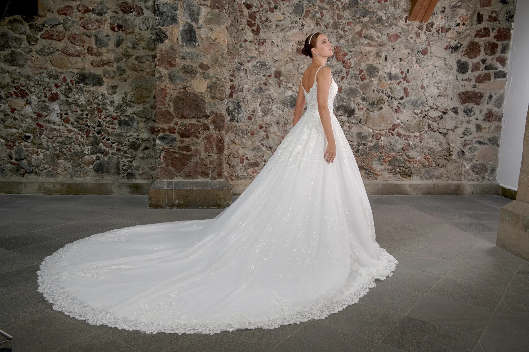 Vista lateral del vestido de novia Cueto mostrando el volumen de la falda de tul y la cola larga.