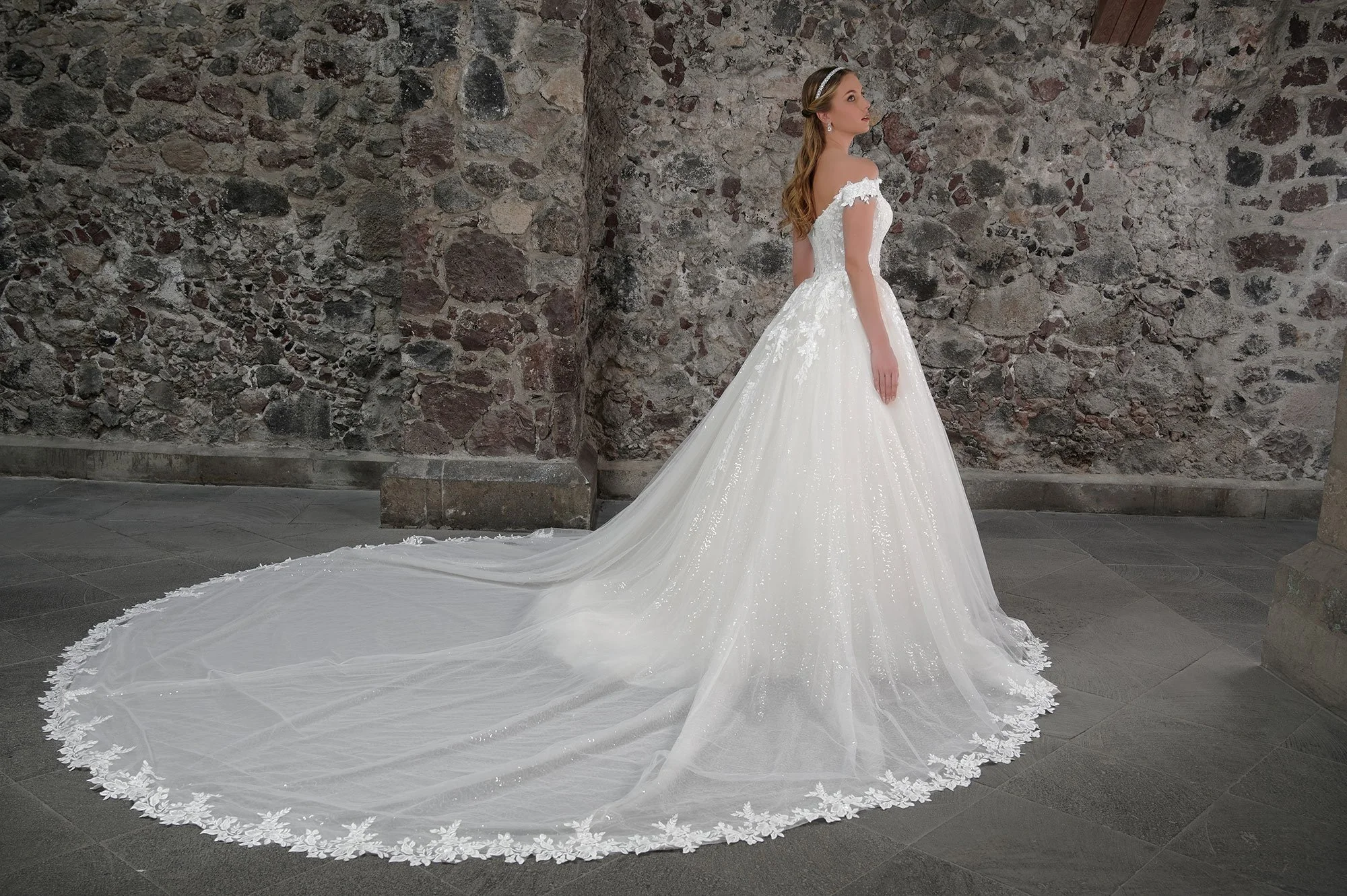 Espalda del vestido de novia Candela con falda de tul brillante y cola larga con encaje.