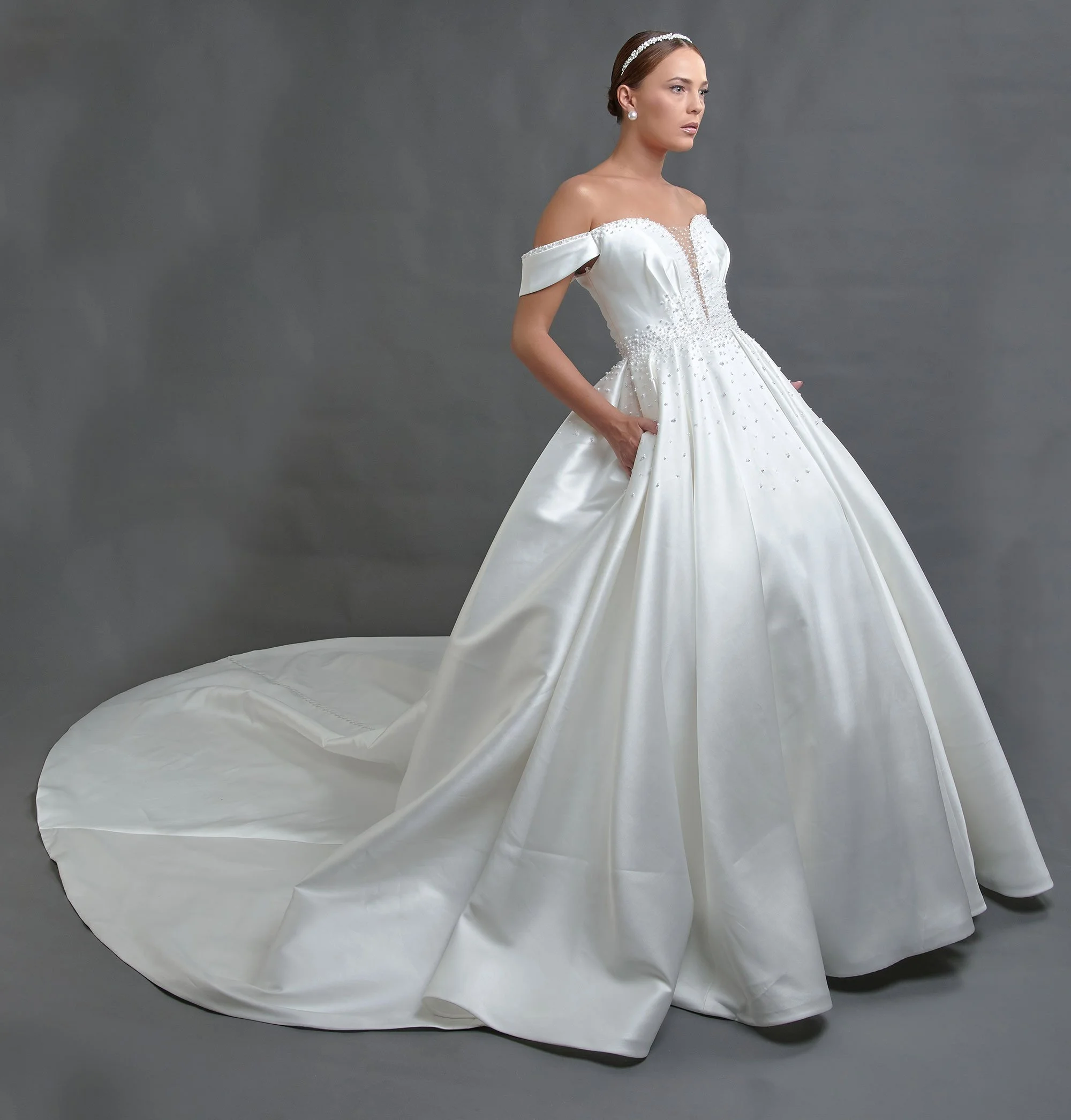 Novia con el vestido Bailen de Bridenformal, princesa de satén con pedrería y mangas caídas, vista frontal con cola.