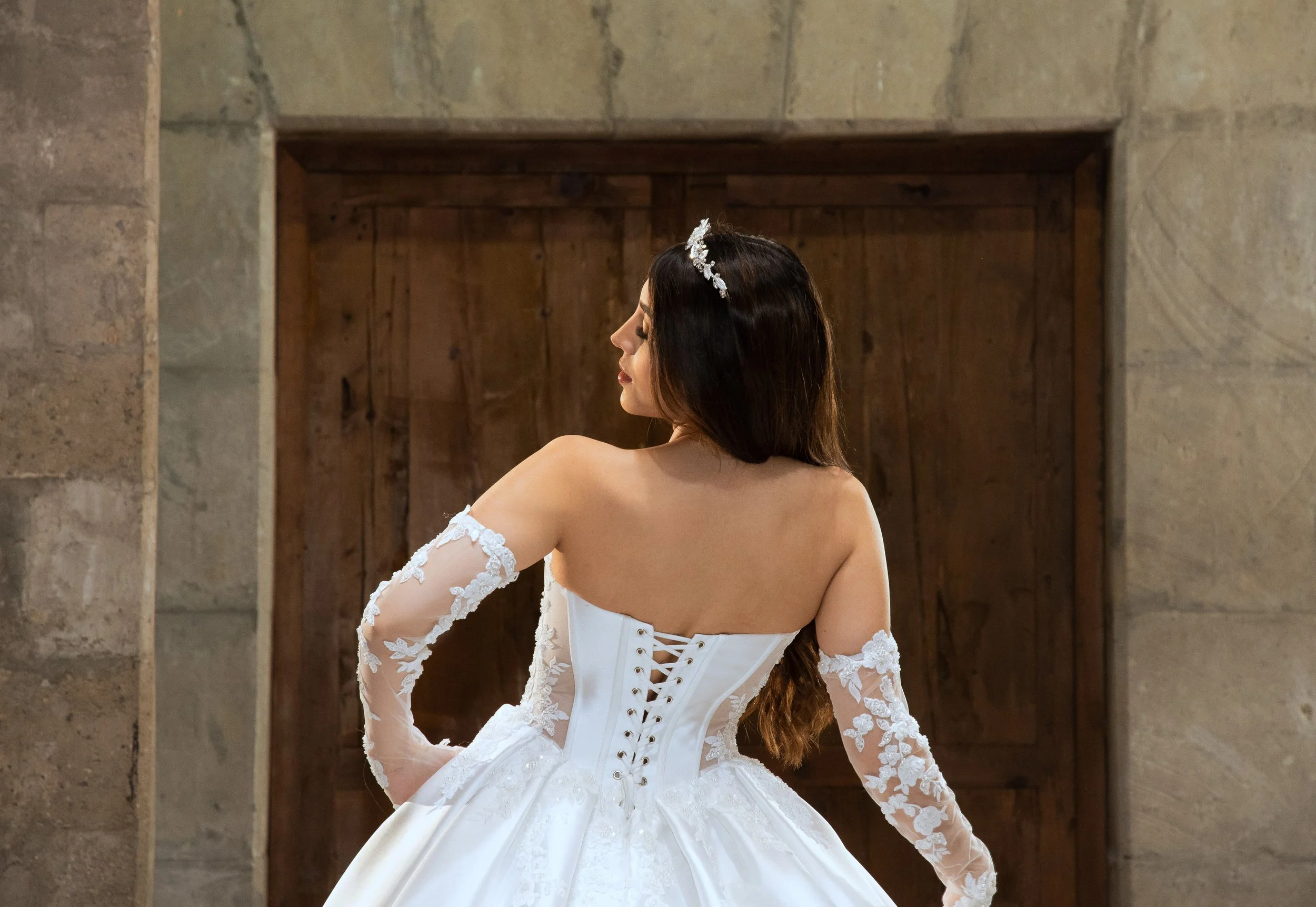 Espalda del vestido Leonor con la cola desplegada, rematada en encaje floral, y amarre de listón.