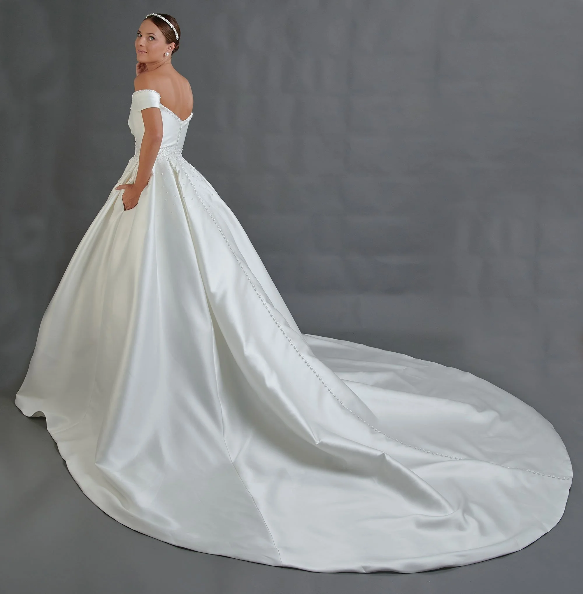 Espalda del vestido de novia Bailen con falda amplia de satén y cola larga envolvente.