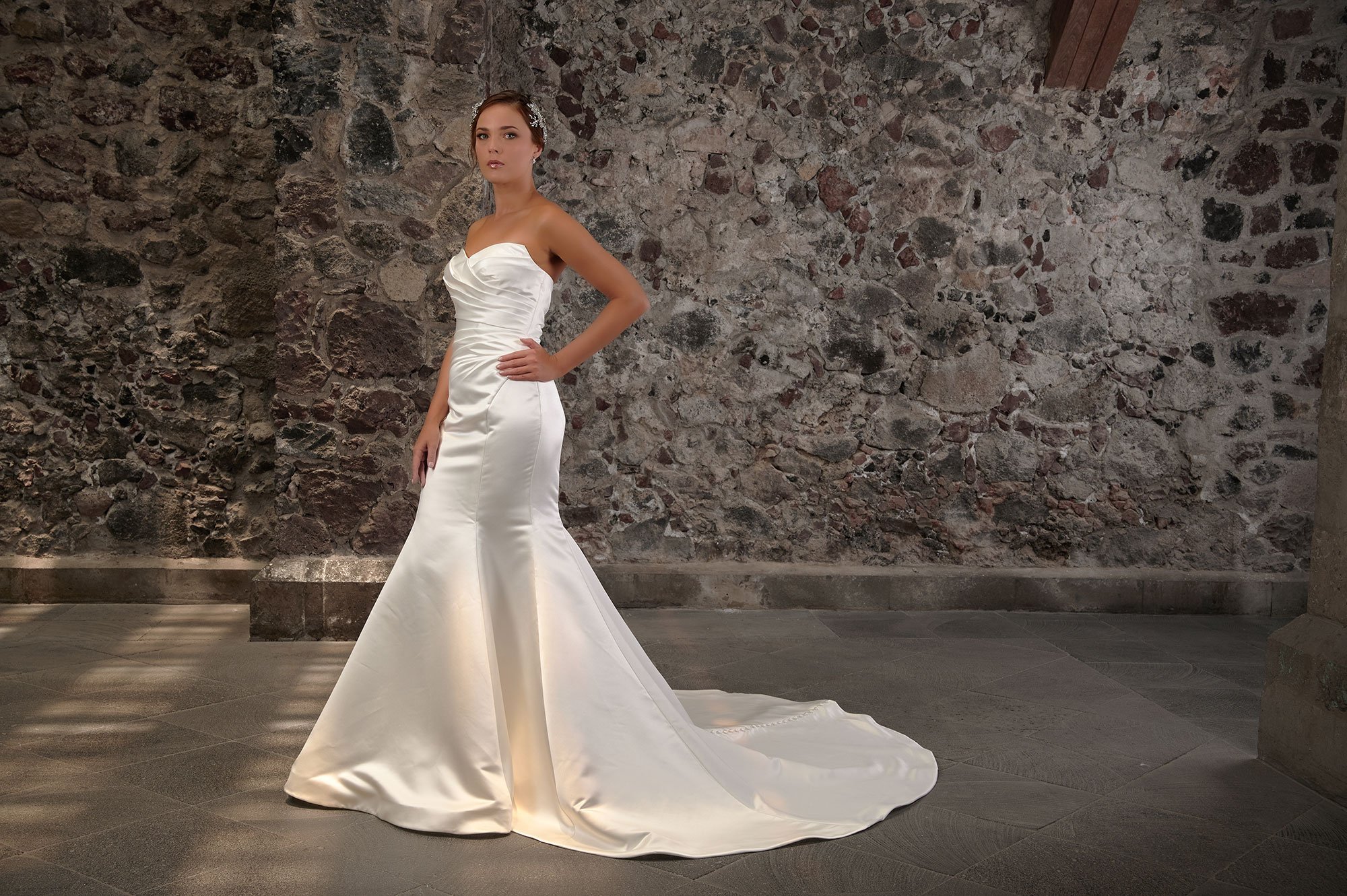 Novia con el vestido Cibeles de Bridenformal, silueta sirena de satén con escote corazón strapless, vista frontal con cola.