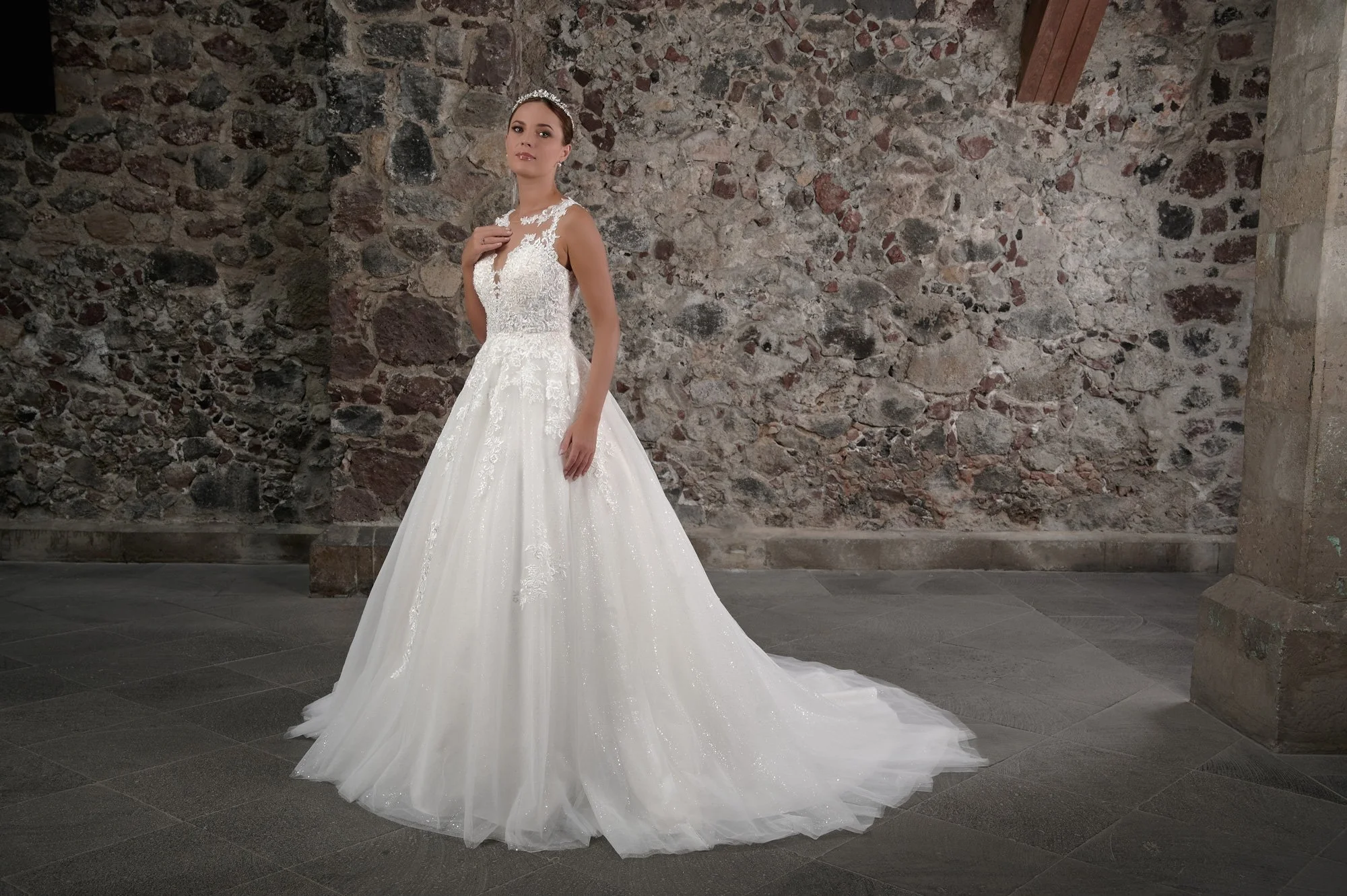 Novia con el vestido Coco de Bridenformal, princesa de tul con encaje y escote de ilusión en V, vista frontal con cola.
