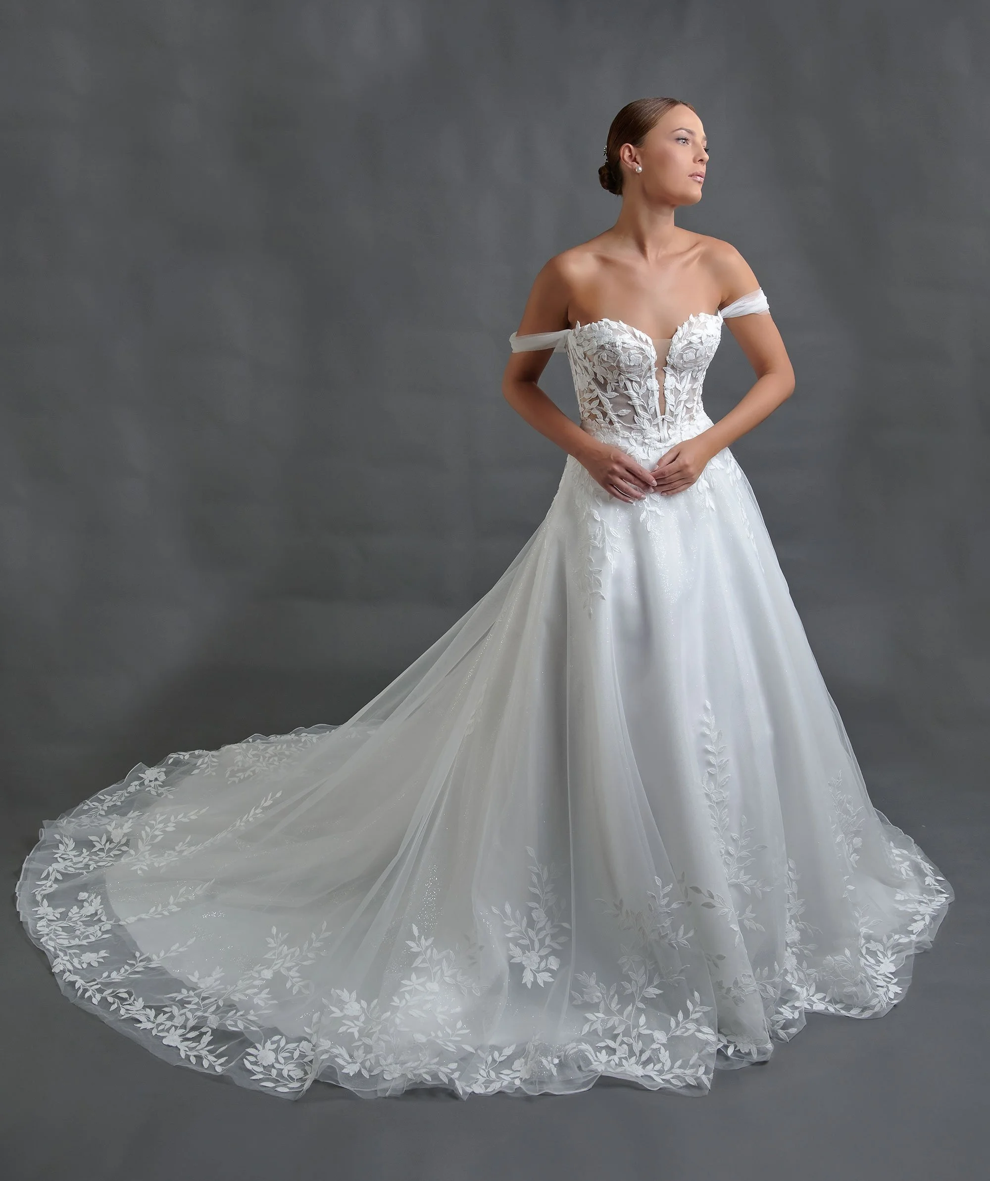 Novia con el vestido Belina de Bridenformal, línea A de tul con corsé de encaje y hombros caídos, vista frontal completa.