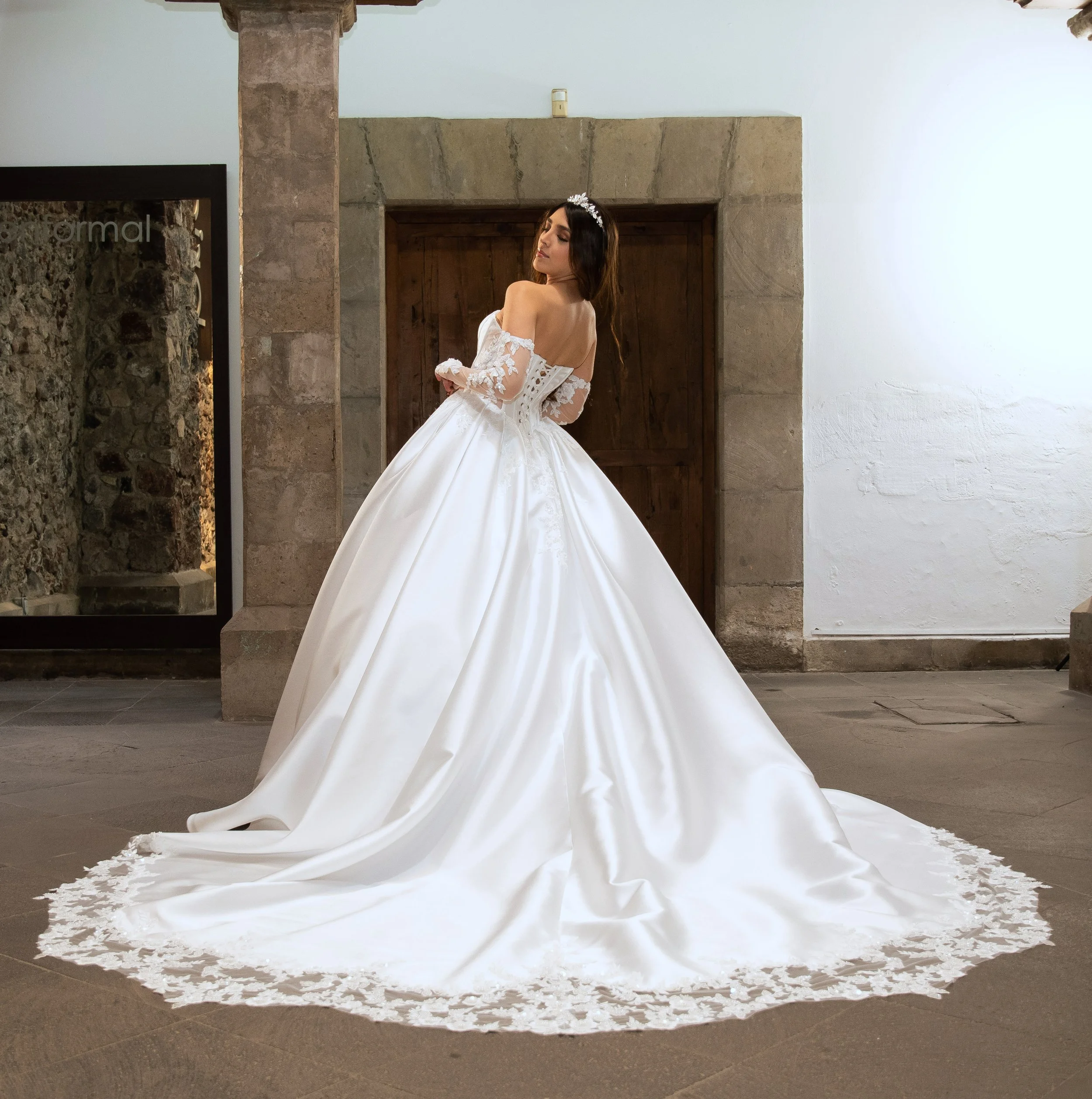 Espalda del vestido Leonor con la cola desplegada, rematada en encaje floral, y amarre de listón.
