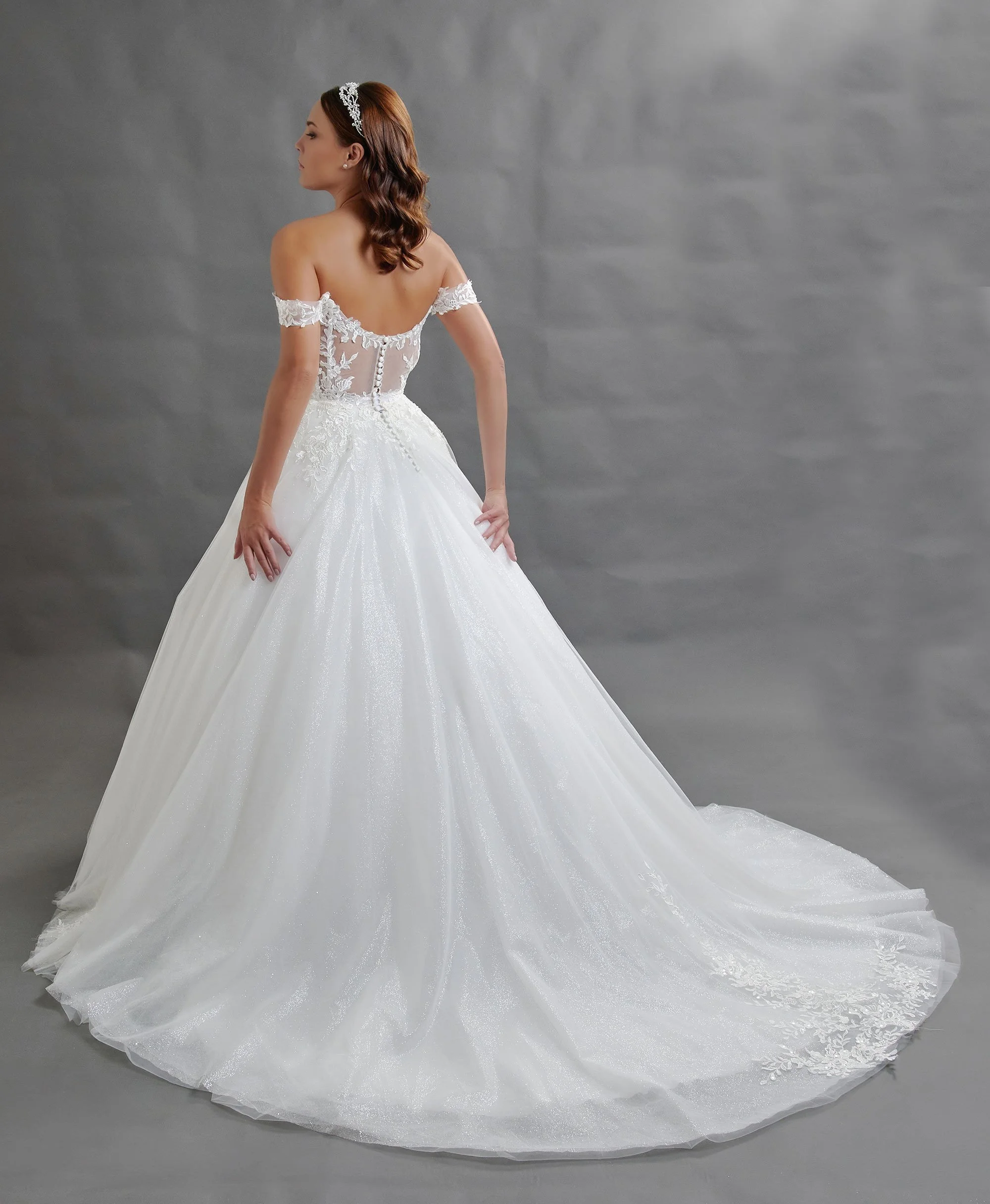 Espalda del vestido de novia Baeza con falda princesa de tul brillante y cola larga con apliques de encaje.