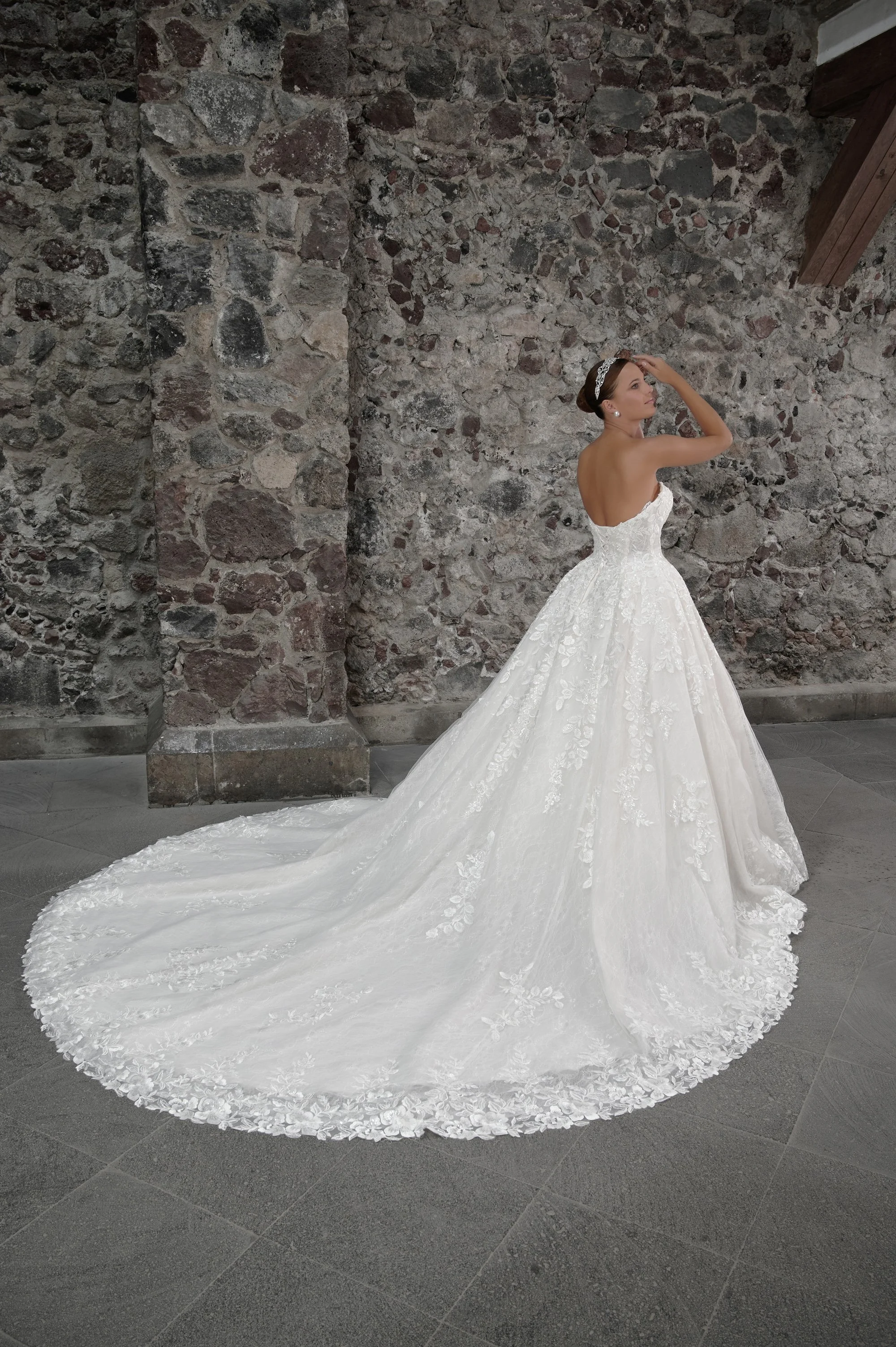 Espalda descubierta del vestido Calvin con falda princesa de encaje y cola larga extendida.