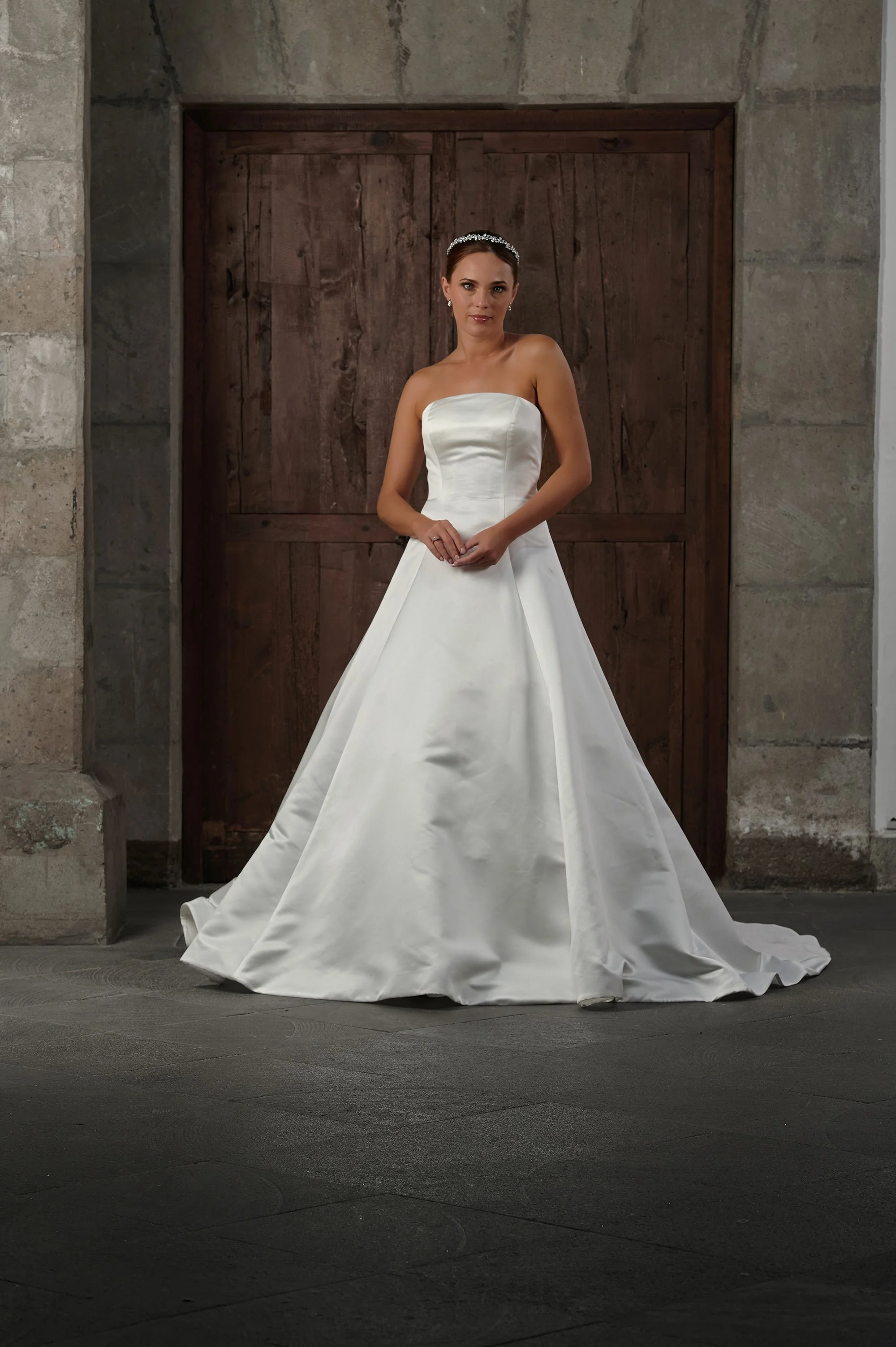 Novia con el vestido Qendal de Bridenformal, princesa strapless de satén liso, vista frontal con cola.