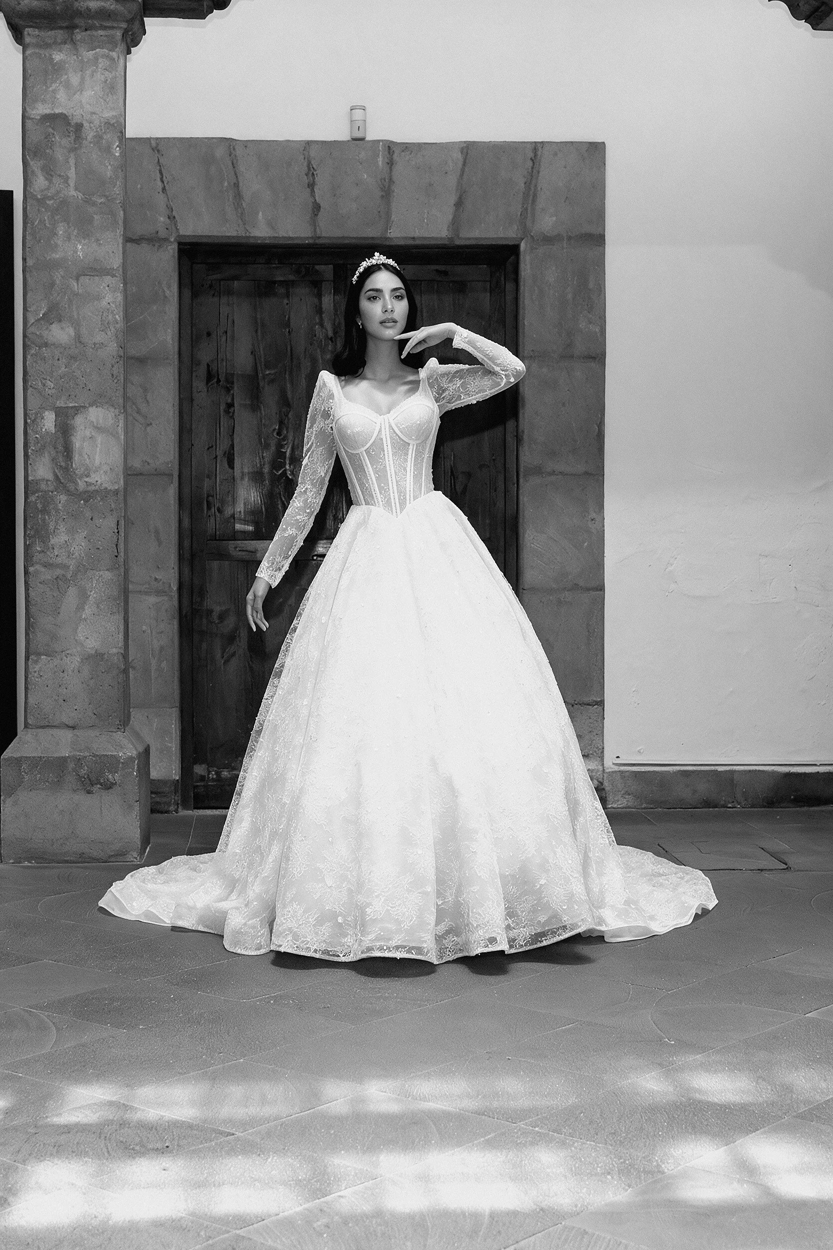 Novia con el vestido Luna de Bridenformal, silueta princesa con brillo y mangas largas de encaje, vista frontal completa.
