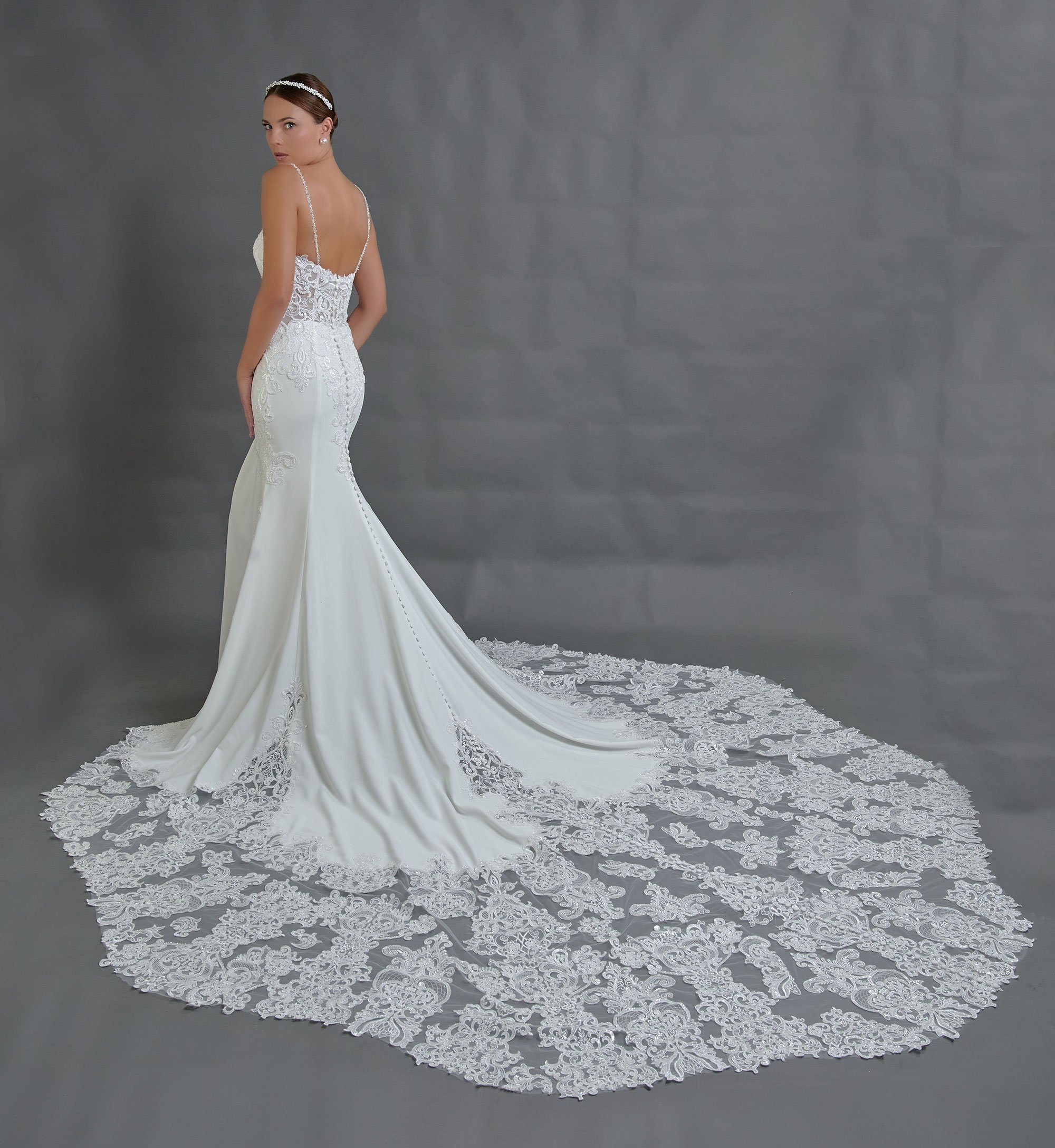 Espalda del vestido de novia Beterra con espalda descubierta, botones forrados y cola larga de encaje festoneado.