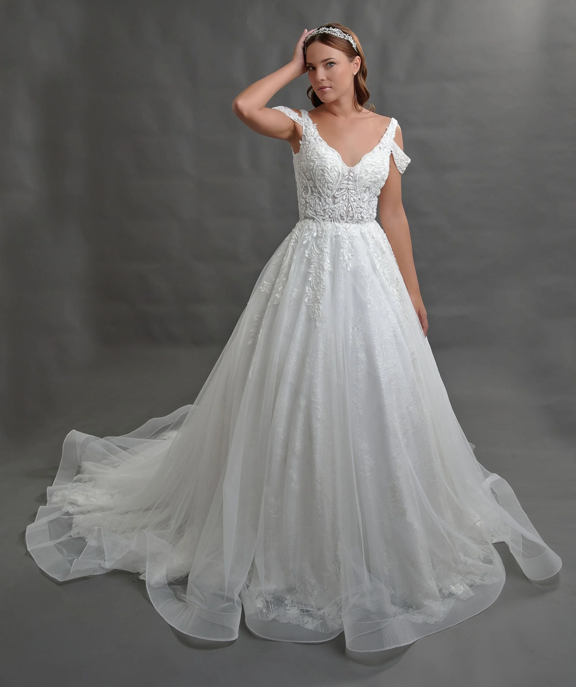 Novia con el vestido Berlange de Bridenformal, princesa de tul con brillo y mangas caídas de encaje, vista frontal con cola.