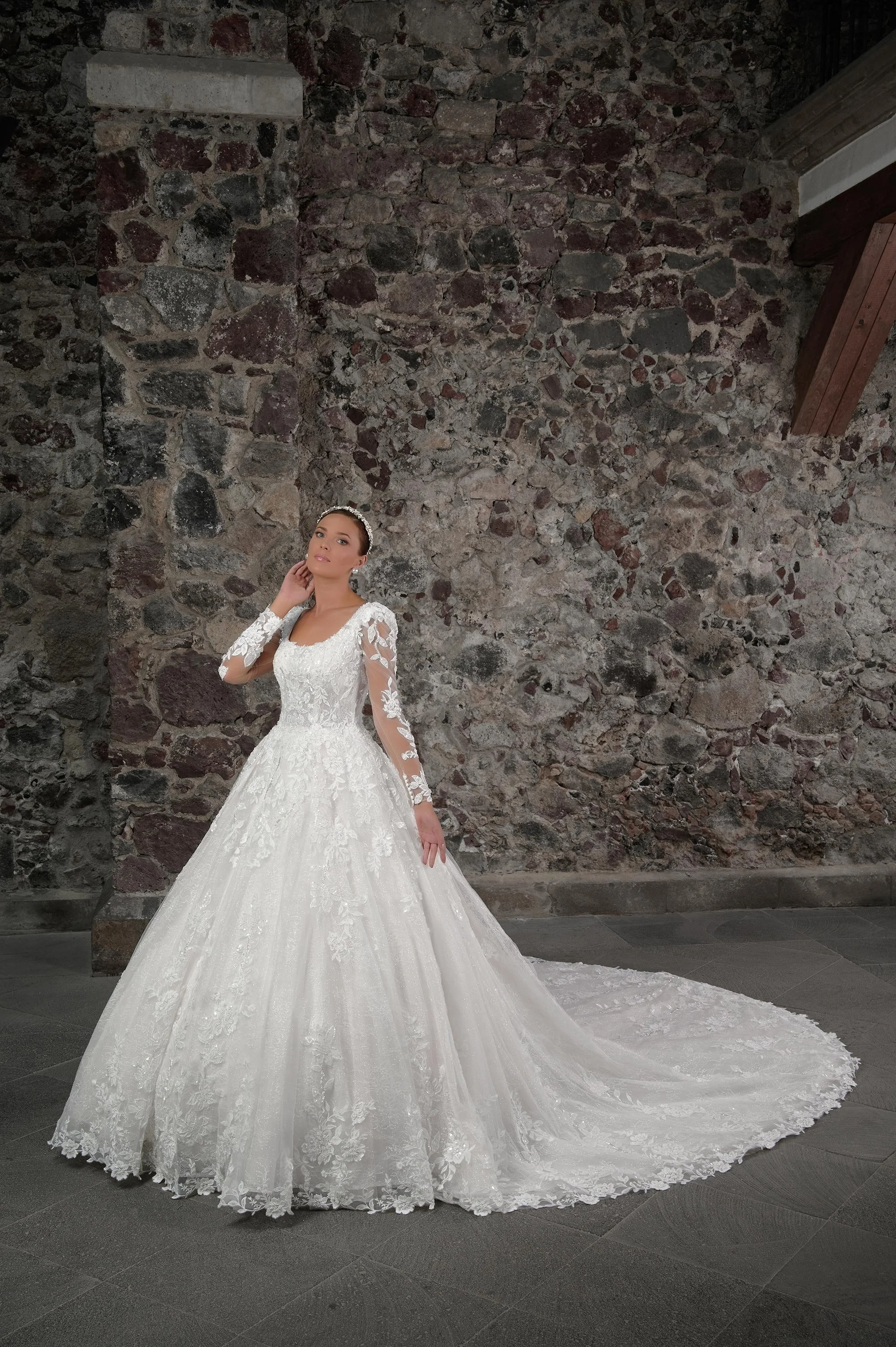 Novia con el vestido Cedric de Bridenformal, princesa de manga larga con encaje floral bordado, vista frontal con cola.