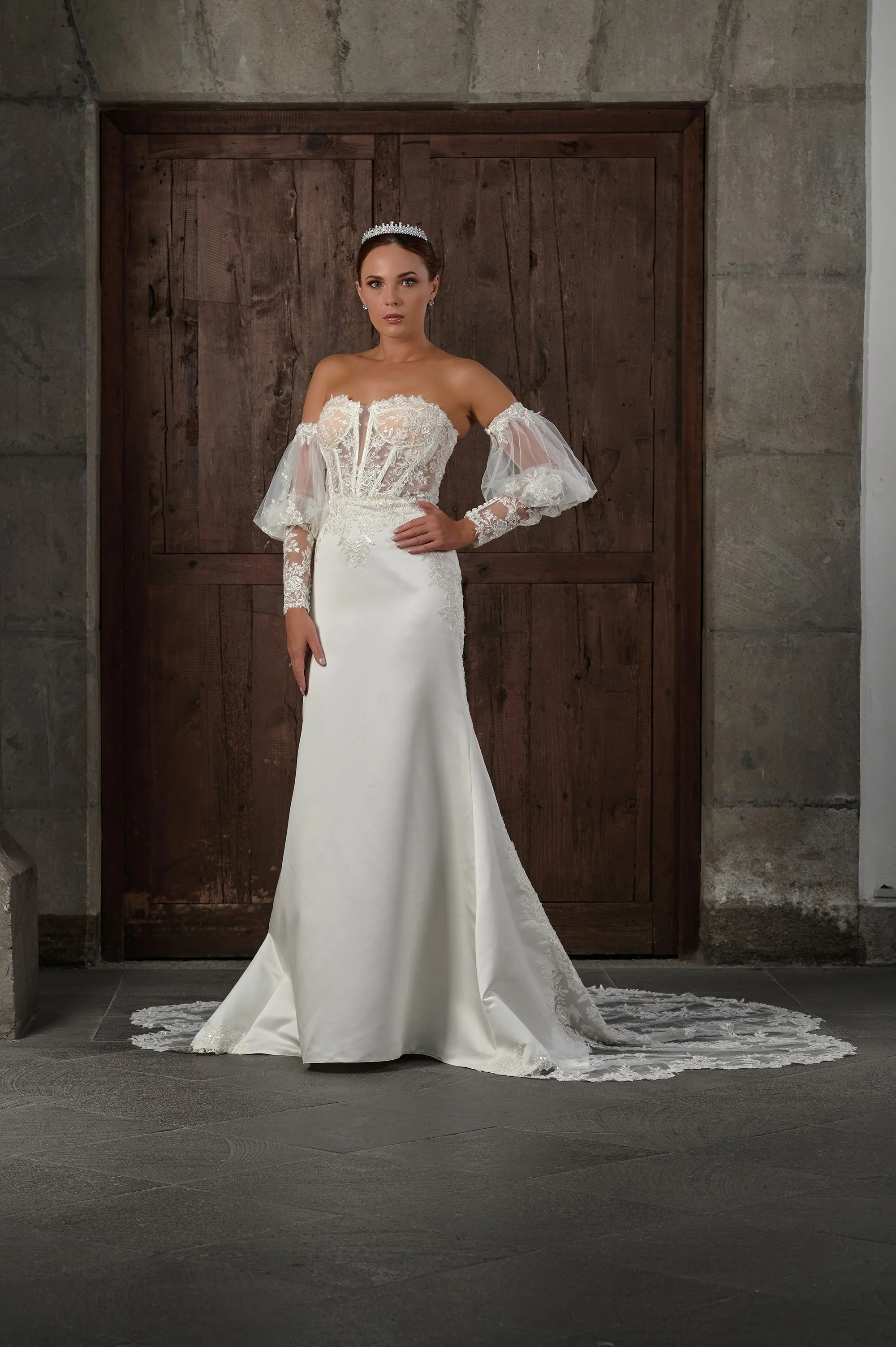 Novia con el vestido Qeila de Bridenformal, sirena strapless con mangas globo de encaje, vista frontal con cola.