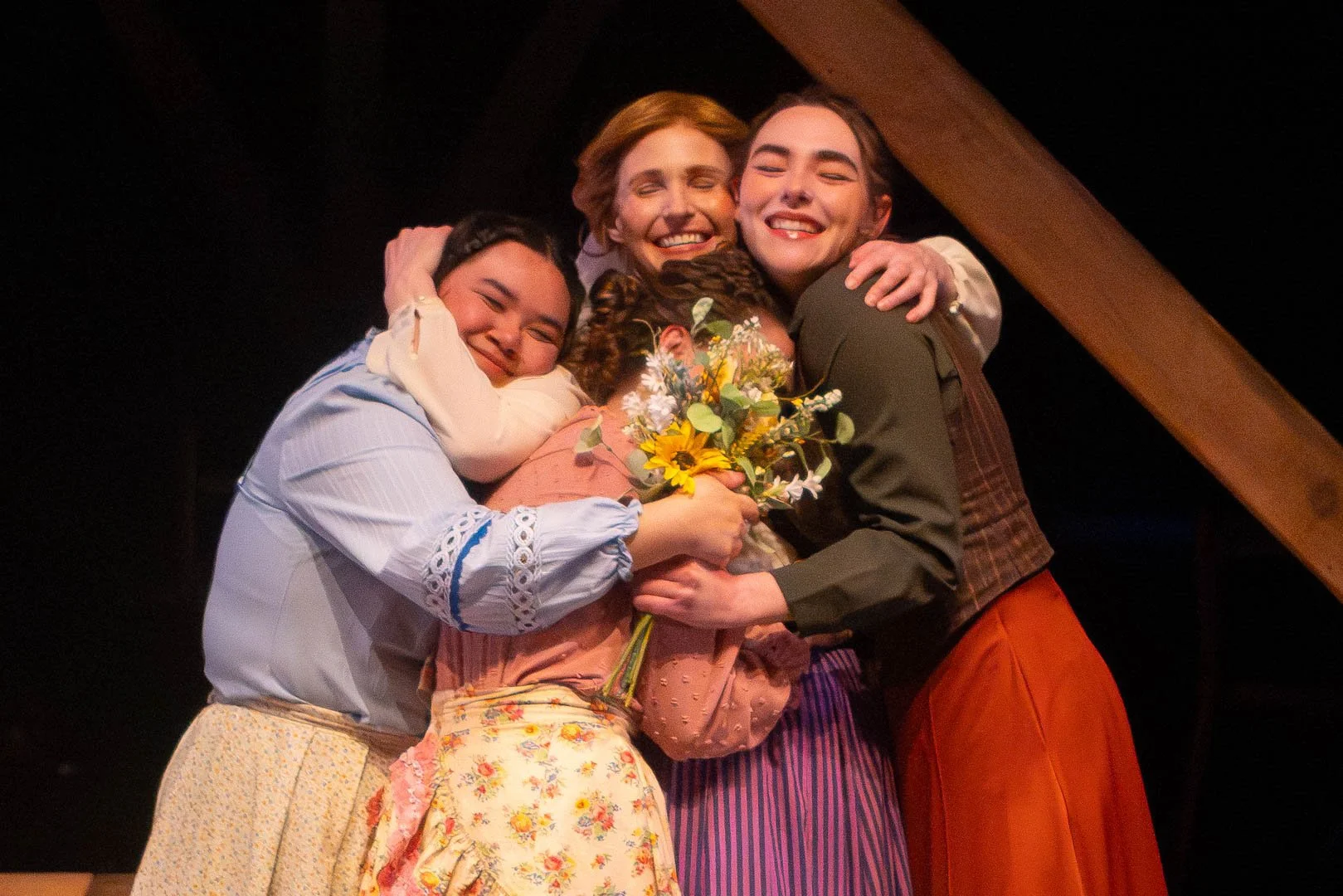 Four people hug.