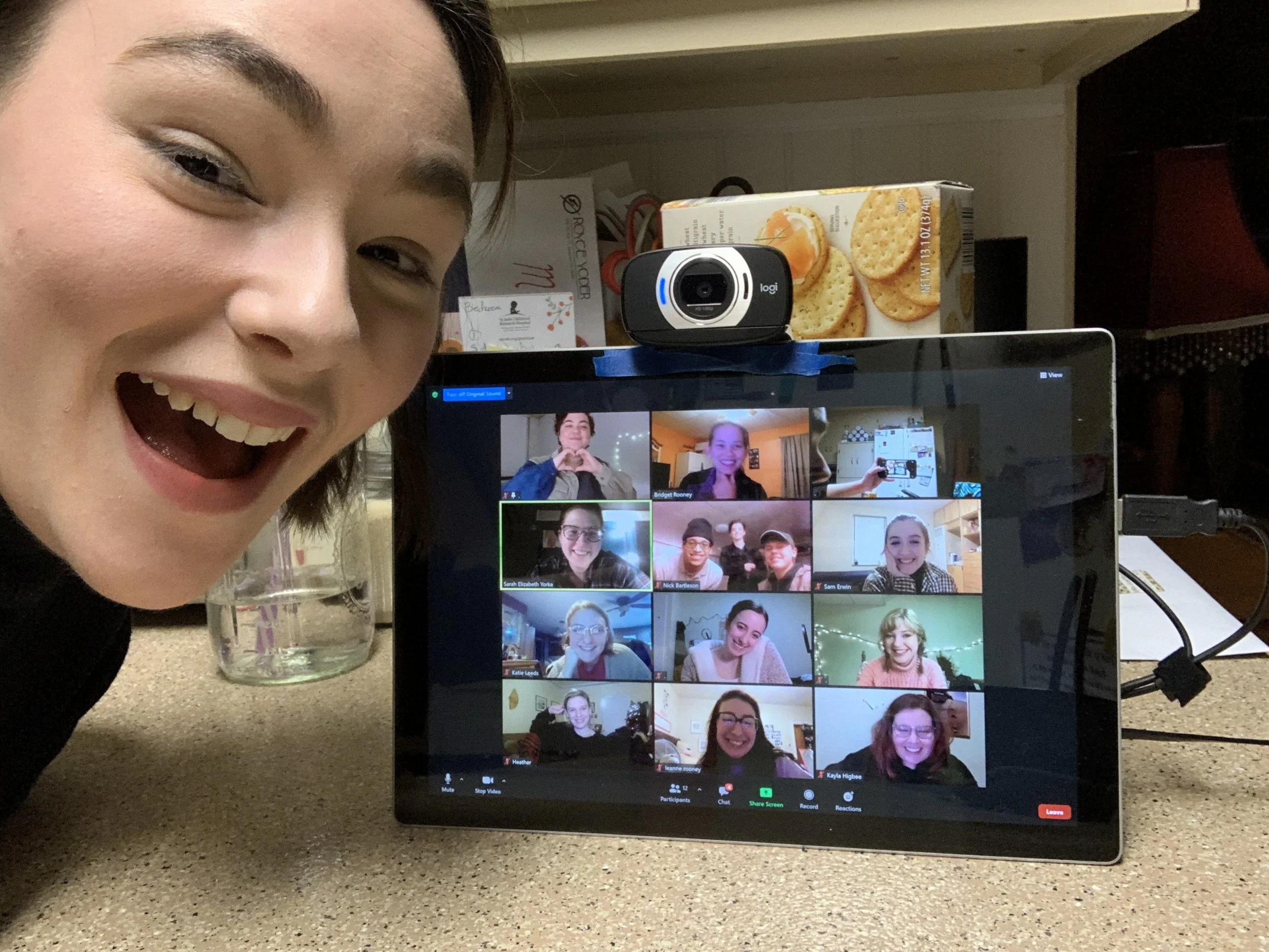 A woman smiles as she video calls with a group of people.