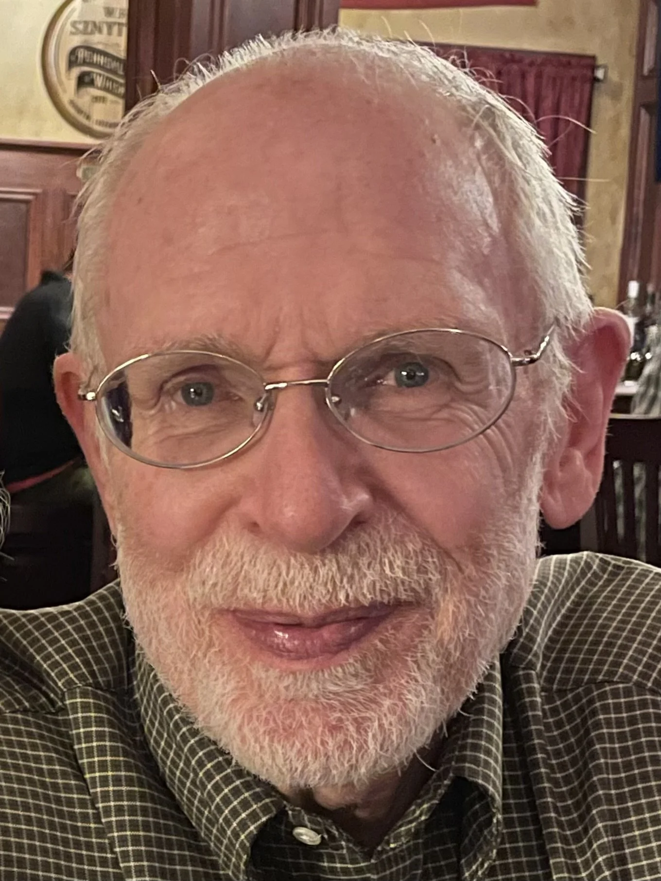  Joel Zeiders, an older white man with oval-shaped glasses smiles at the camera in a restaurant.