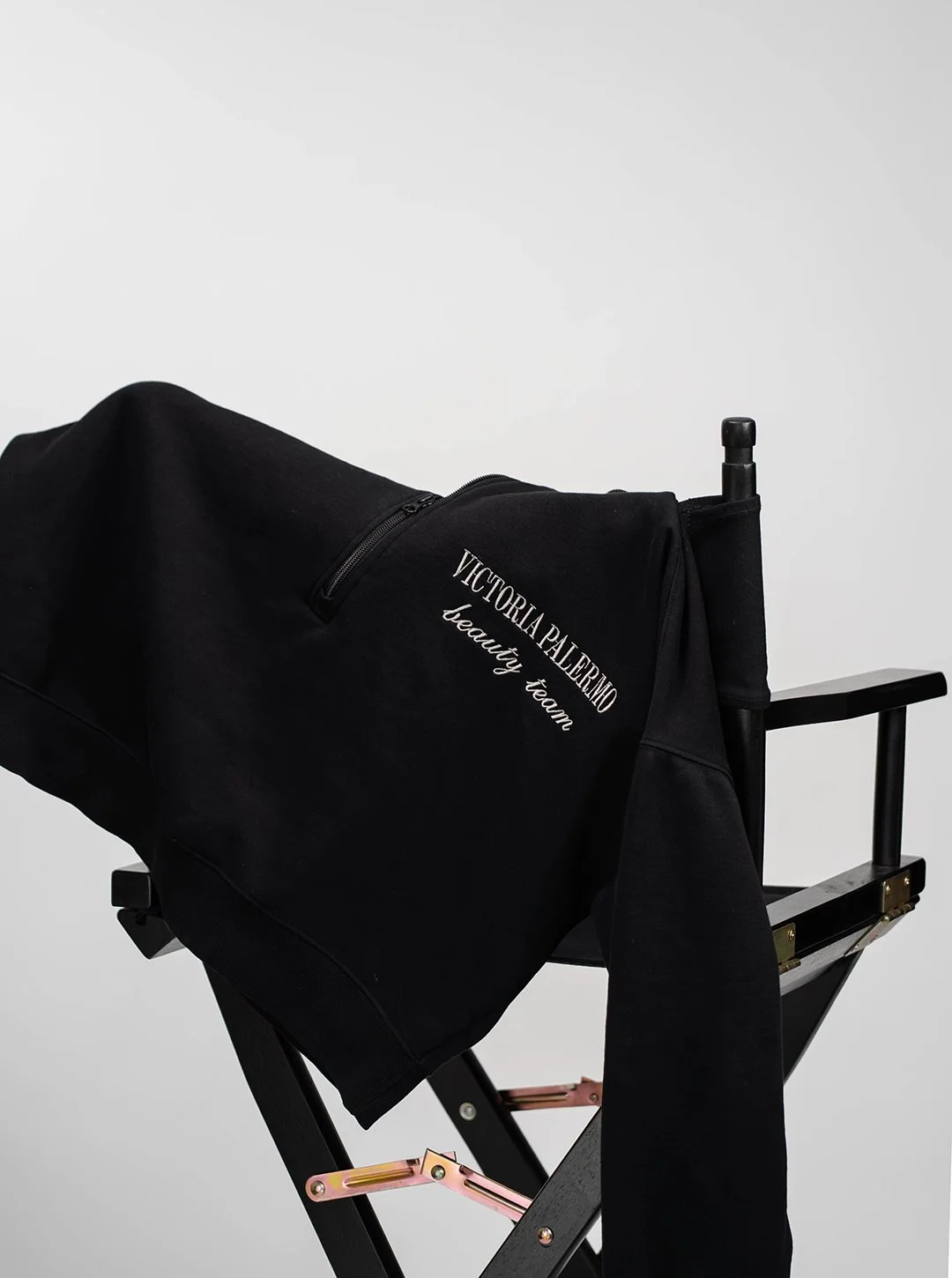Black Victoria Palmero beauty team bag draped over a black director's chair against a plain white background.