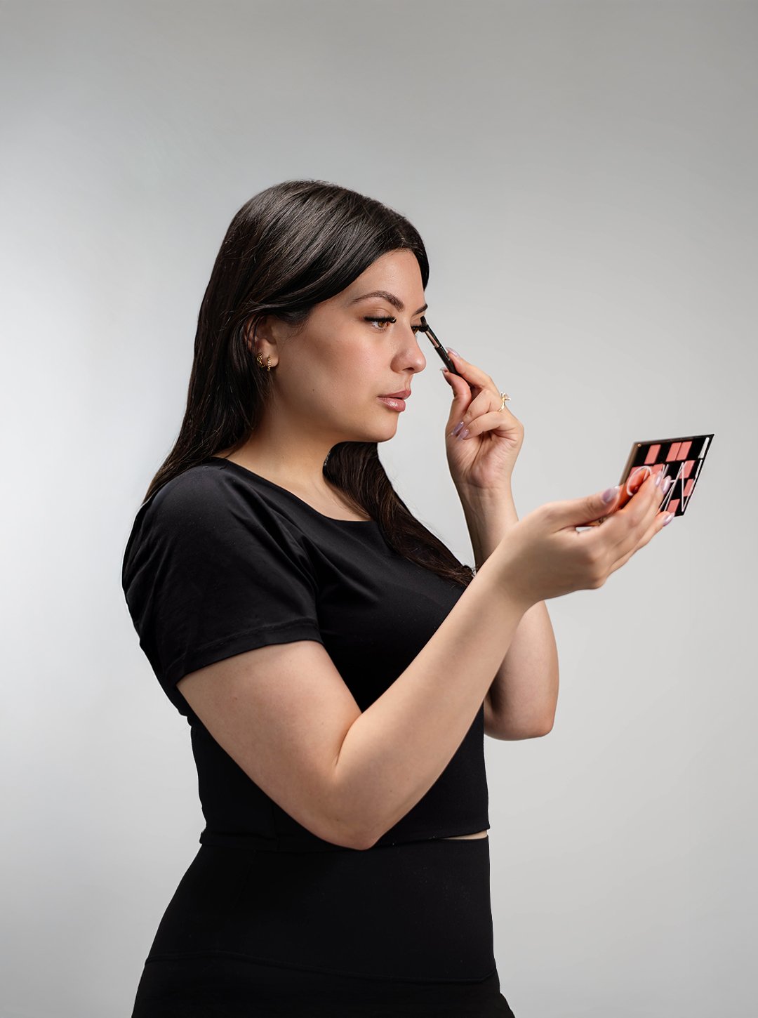 A woman applying makeup while looking into a mirror.