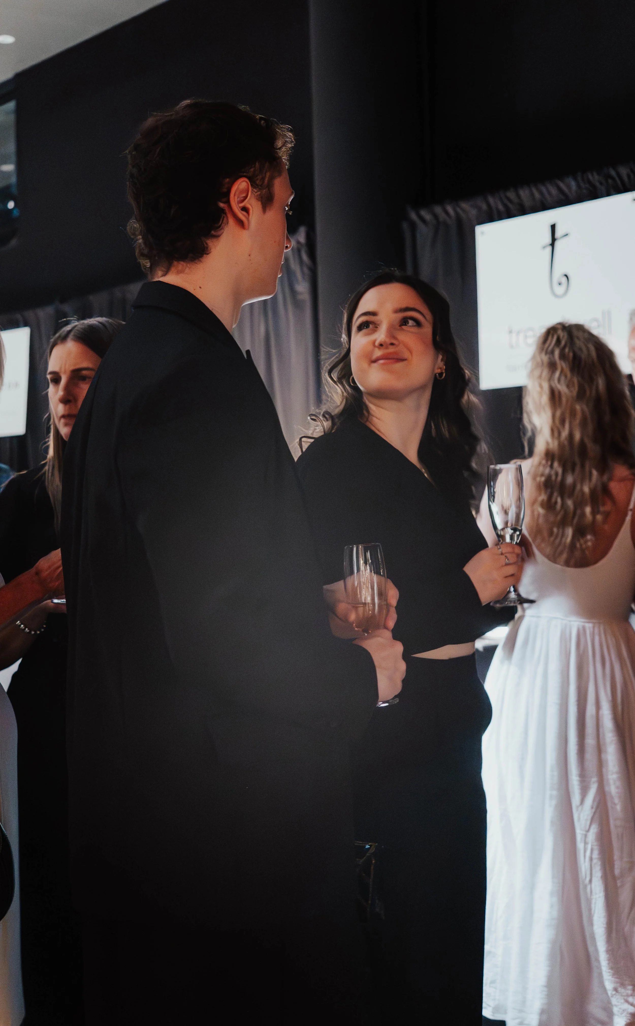 People dressed in formal attire holding champagne glasses at a social event or celebration.