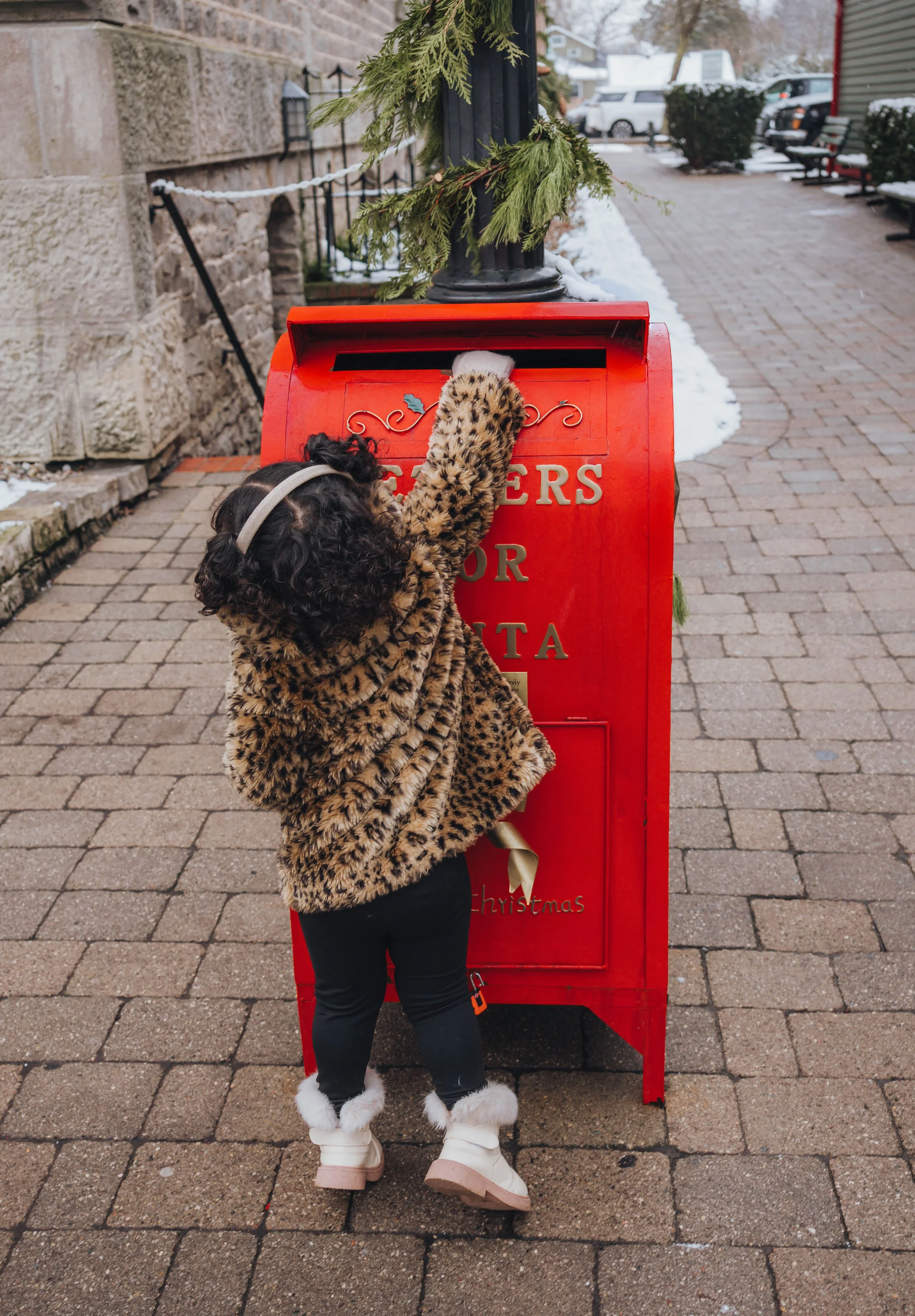 Christmas mini session in Niagara-on-the-Lake featuring a child mailing a letter to Santa in a festive red Christmas mailbox during the holiday season.