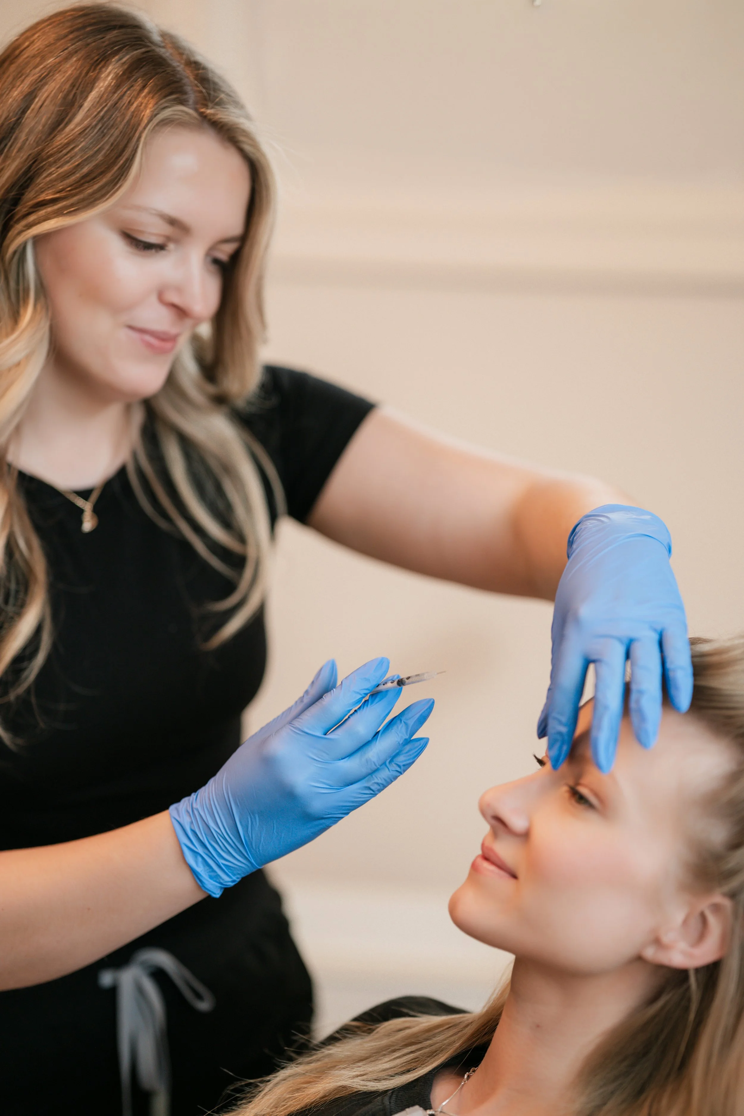 Female injector during a luxury branding photography session in a clean beauty studio with soft natural lighting.