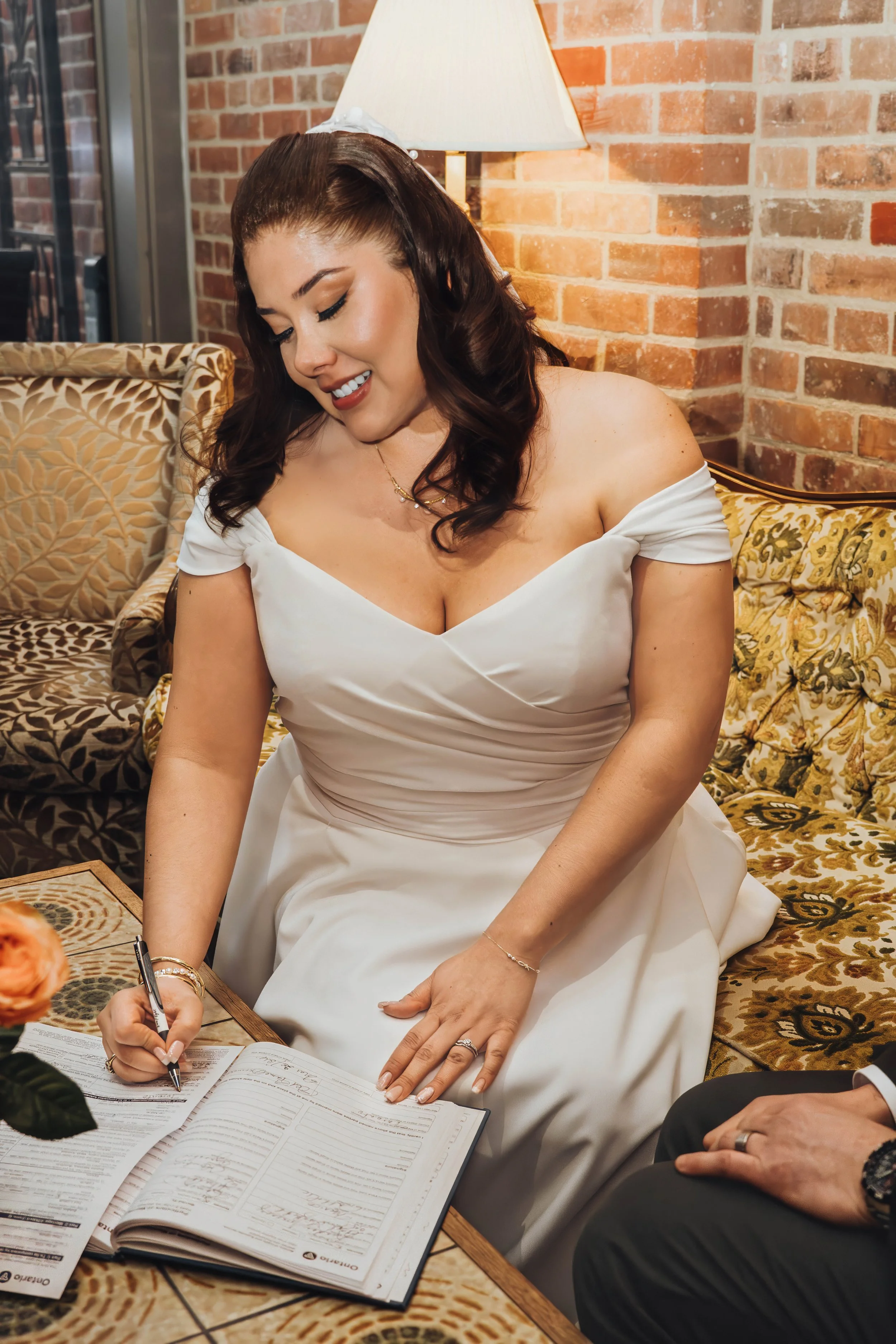 A woman in a white wedding dress signing a book at her wedding.