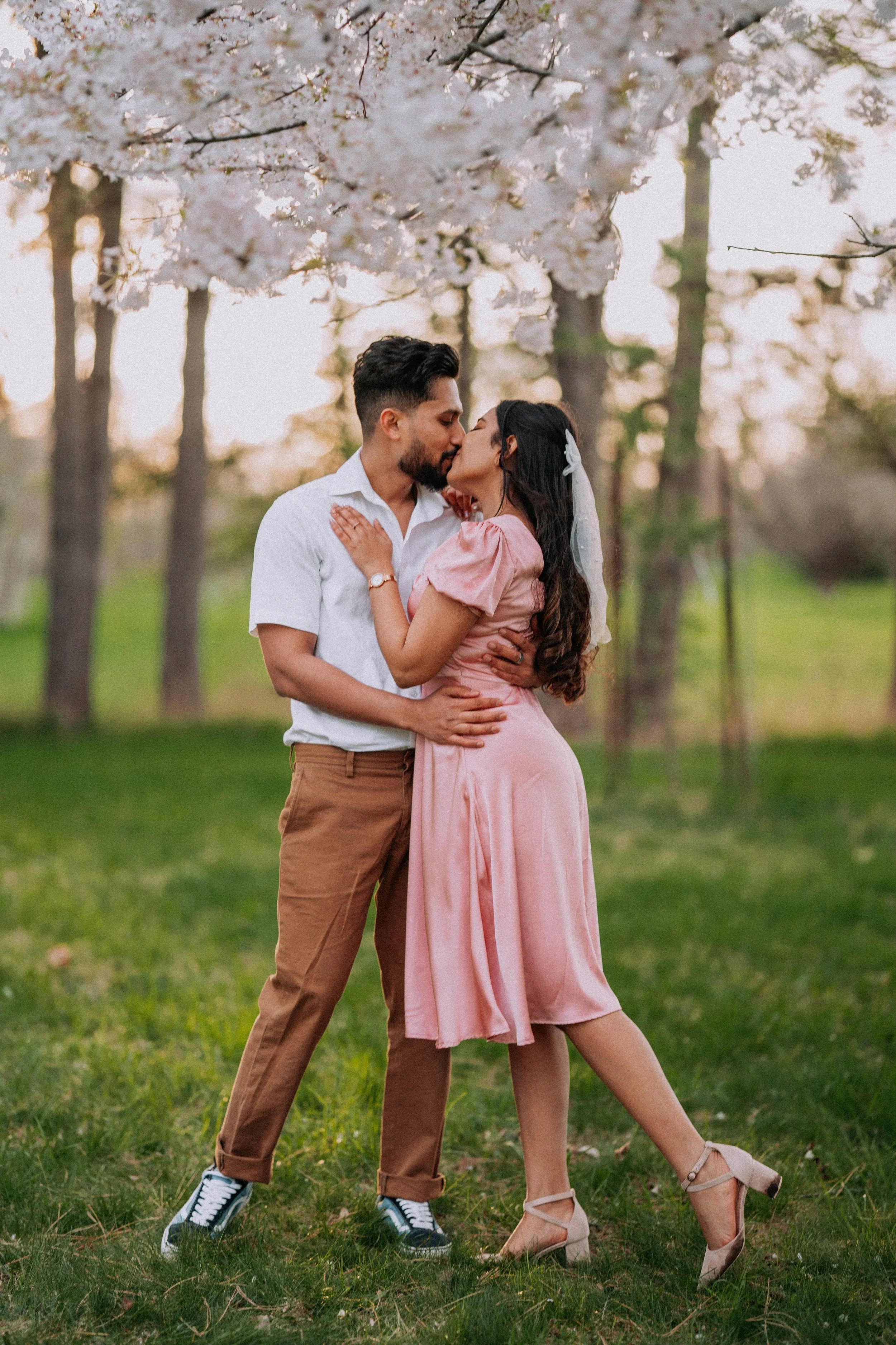 Niagara cherry blossom engagement session with couple embracing and kissing, outdoor spring couple photography in Ontario