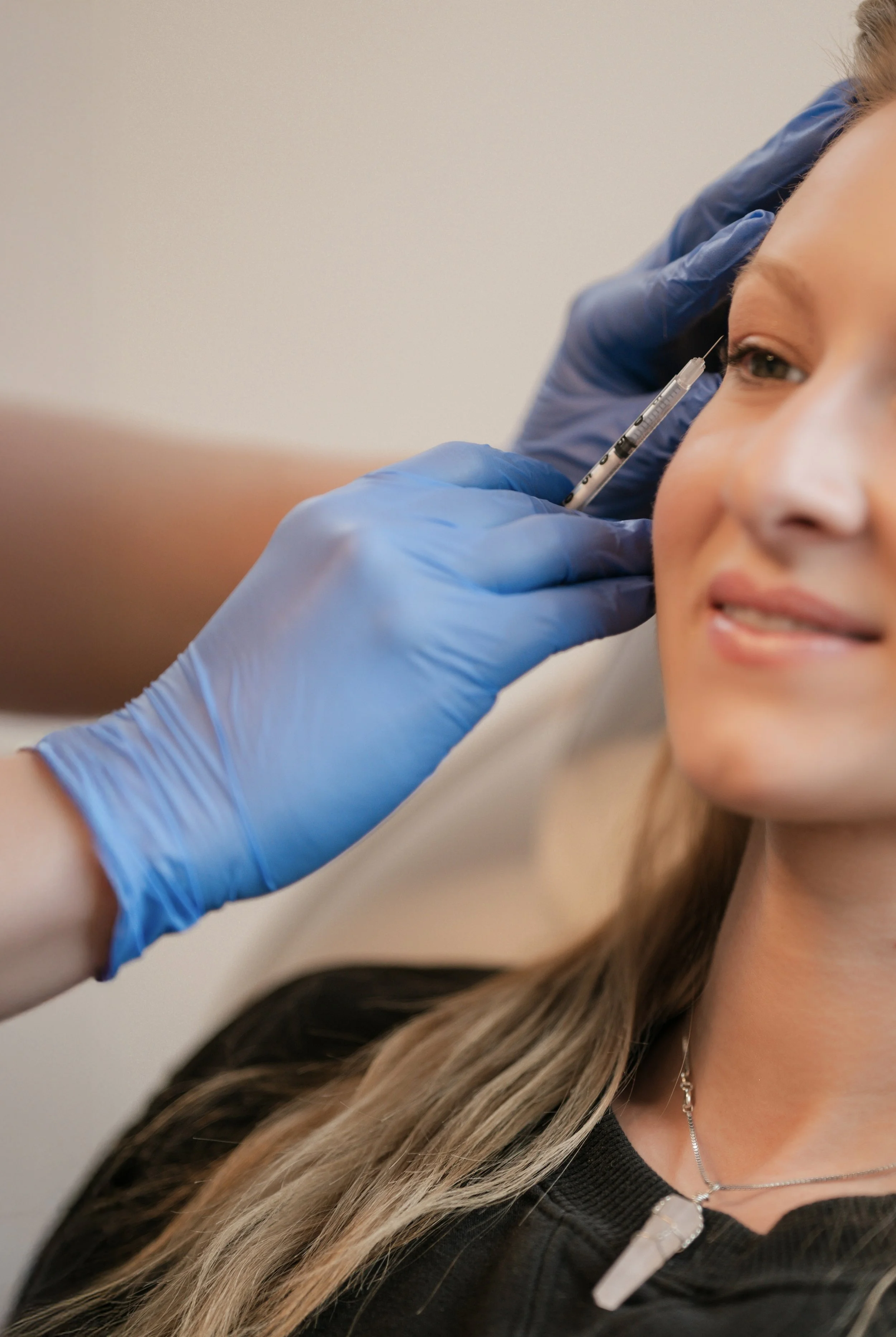 Close-up beauty treatment branding photo featuring a cosmetic injector procedure in a luxury wellness studio.