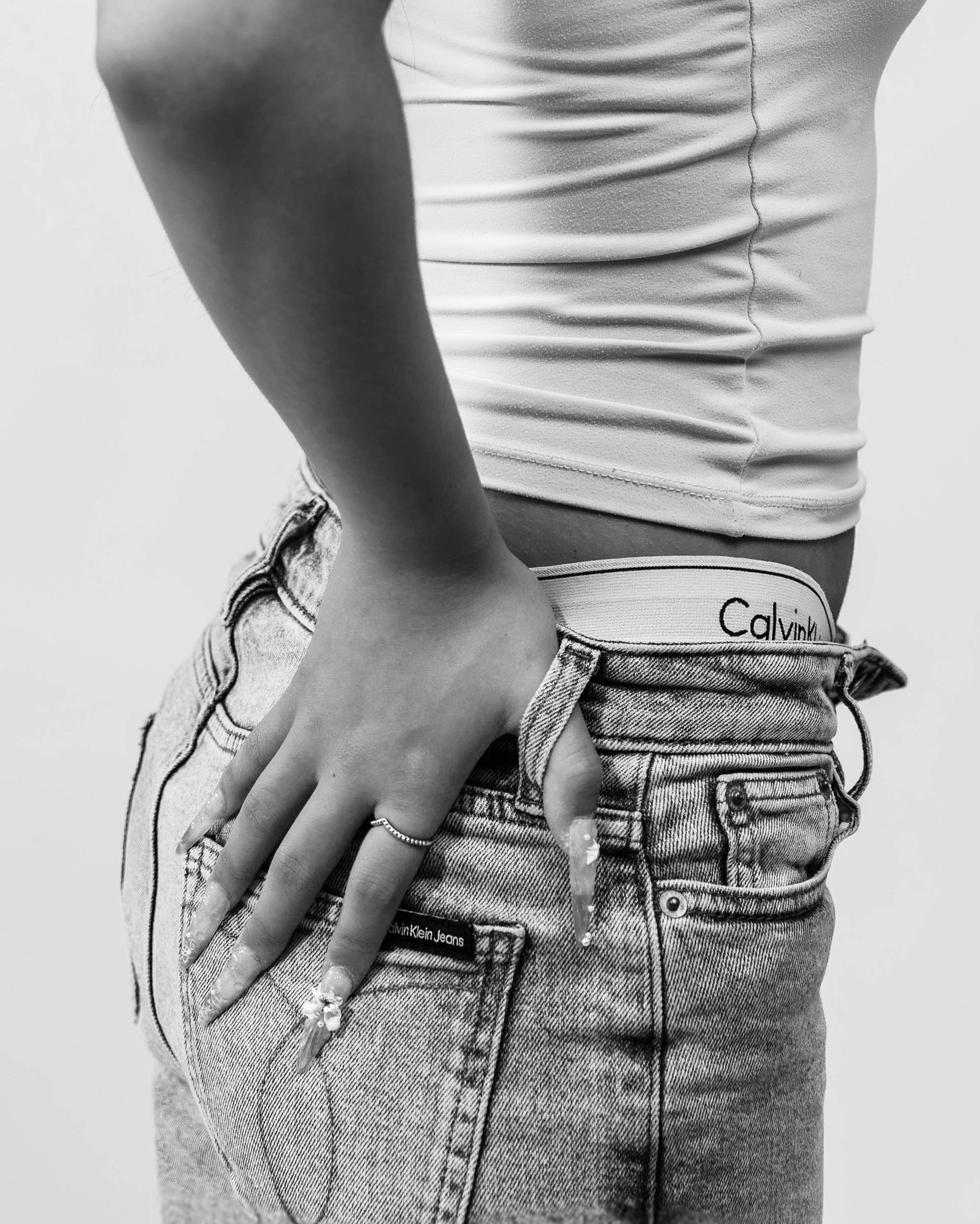 Black and white close-up fashion photograph of Calvin Klein jeans and underwear, featuring Dana’s hand, rings and detailed nail art, photographed during a Calvin Klein-inspired editorial studio shoot by Lara Grace Creative Studio in Toronto.