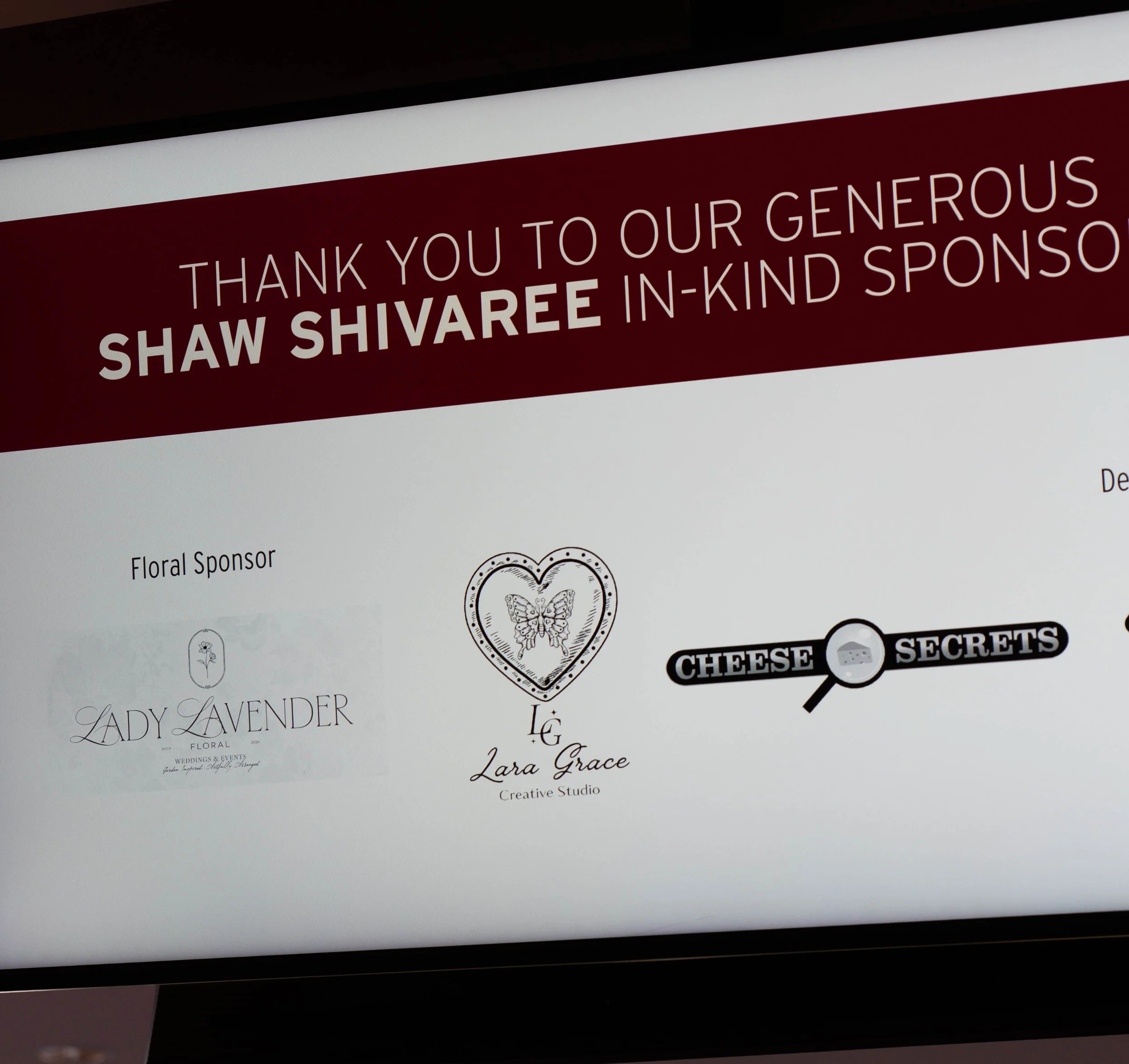 Recognition of sponsors displayed on a screen, including Lady Lavender floral sponsor, Lara Grace Creative Studio logo with butterfly in a heart, and Cheese Secrets logo with a magnifying glass.