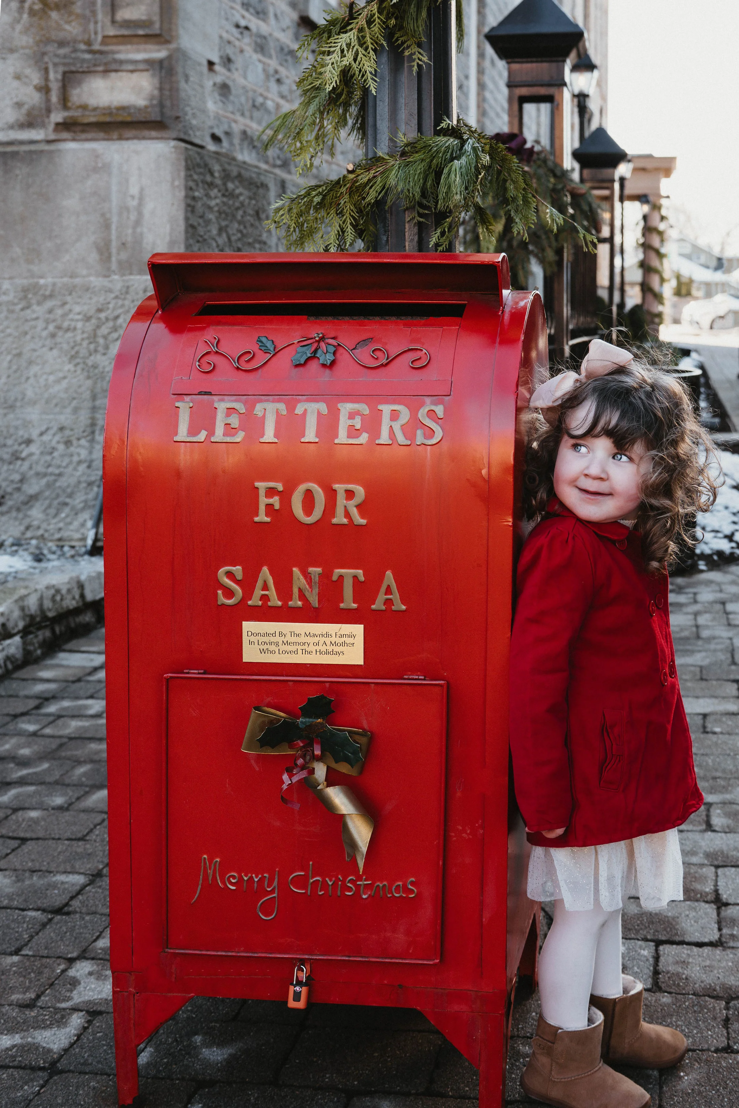 Christmas mini session in Niagara-on-the-Lake with a little girl posing beside the festive Letters for Santa mailbox.
