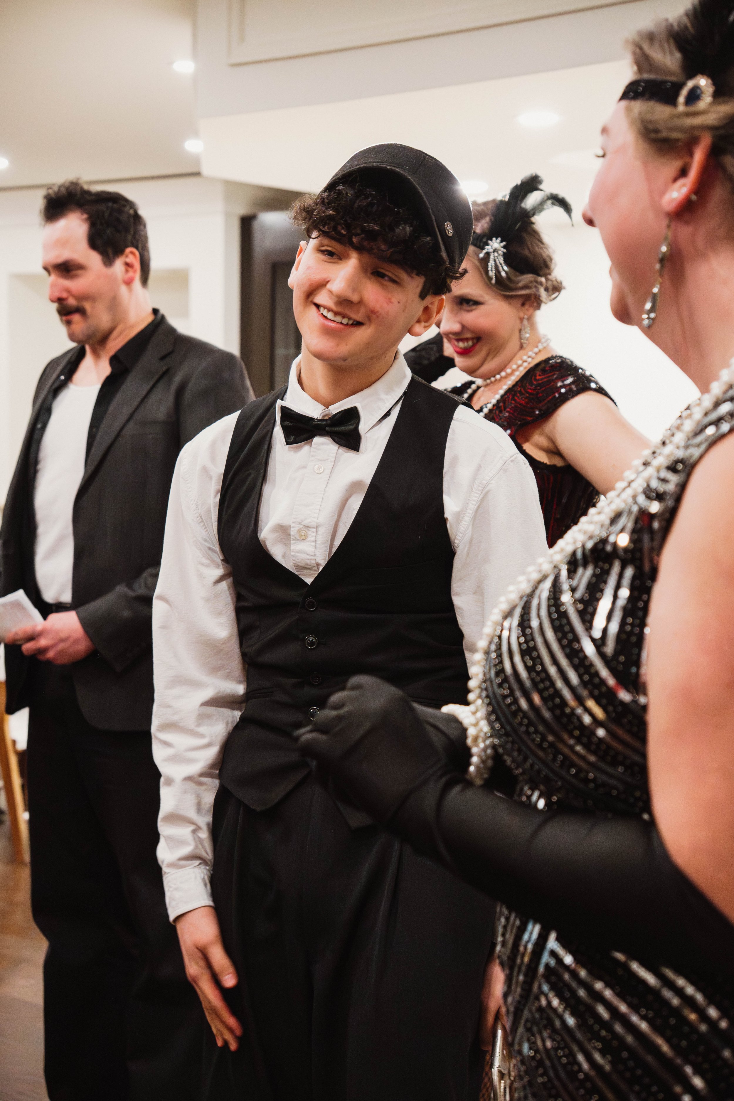 Group of people dressed in vintage fashion at a social gathering, smiling and enjoying conversation.