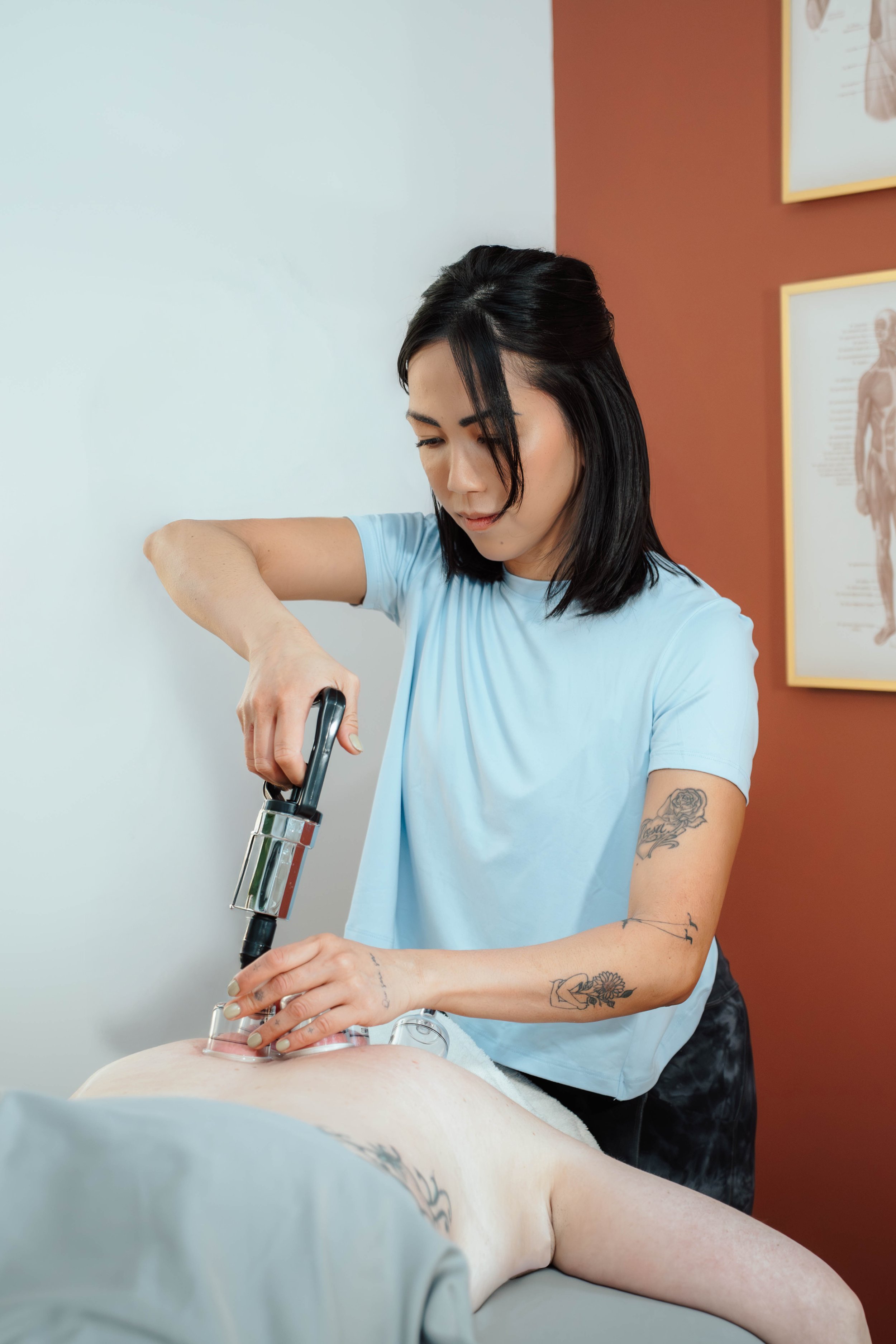 A woman performing a cupping therapy session on a patient lying face down on a treatment table.