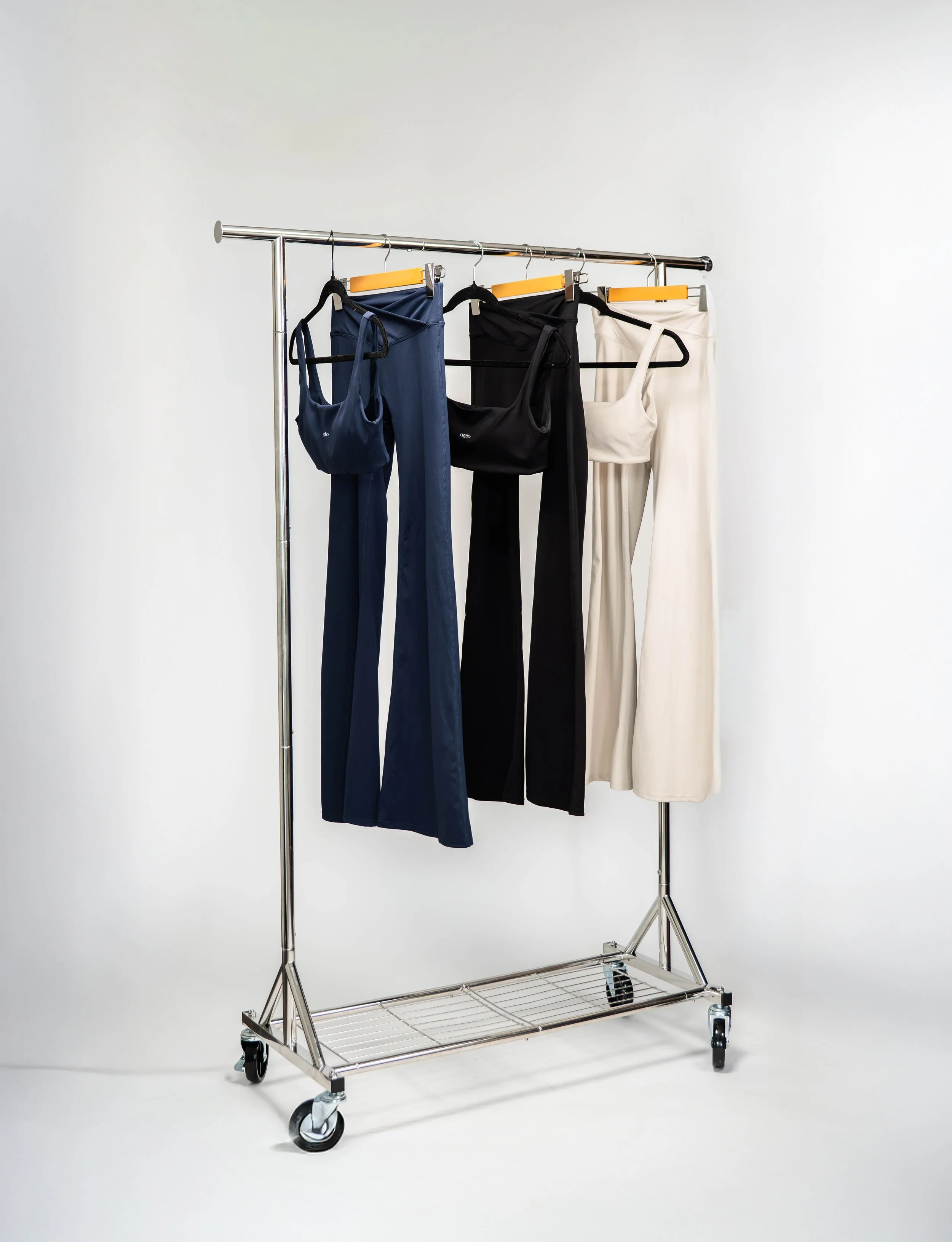 Clothing rack with dresses and matching bags in navy, black, and white against a plain background.