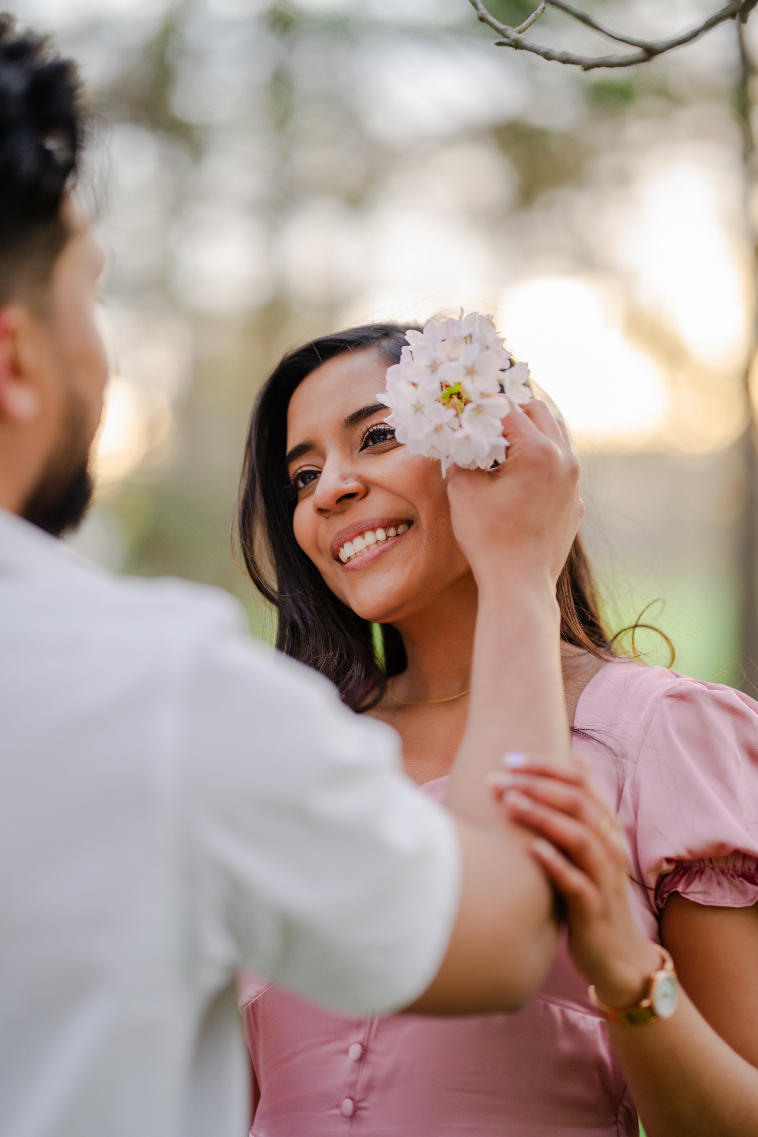 Niagara spring engagement session close-up with woman smiling and cherry blossoms, romantic couple photography in Ontario