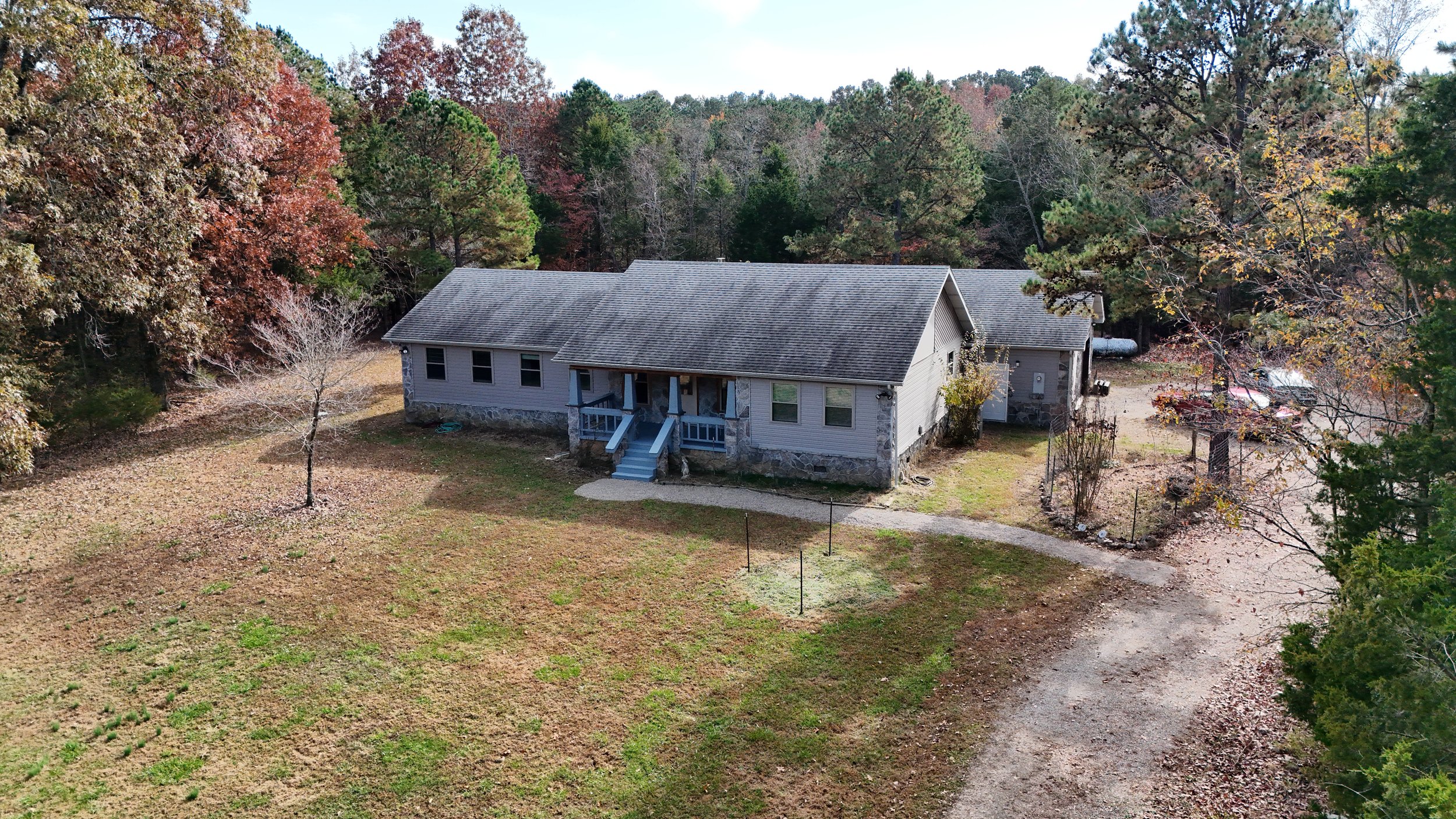 Aerial view of a solitary house amidst a dense woodland, surrounded by trees and nature's tranquility.