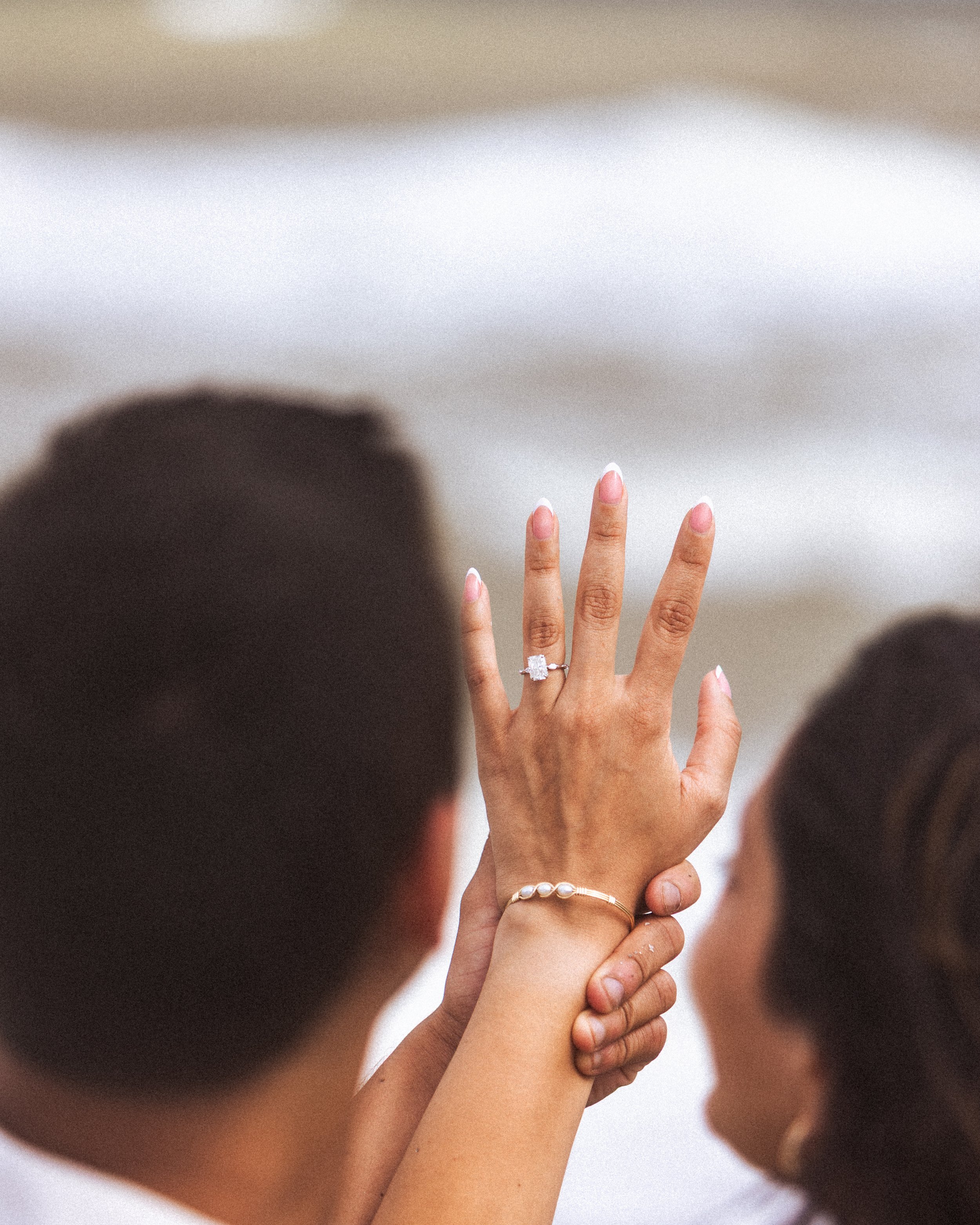 A woman displaying her engagement ring during a wedding ceremony, with her hand raised showing the ring on her finger.